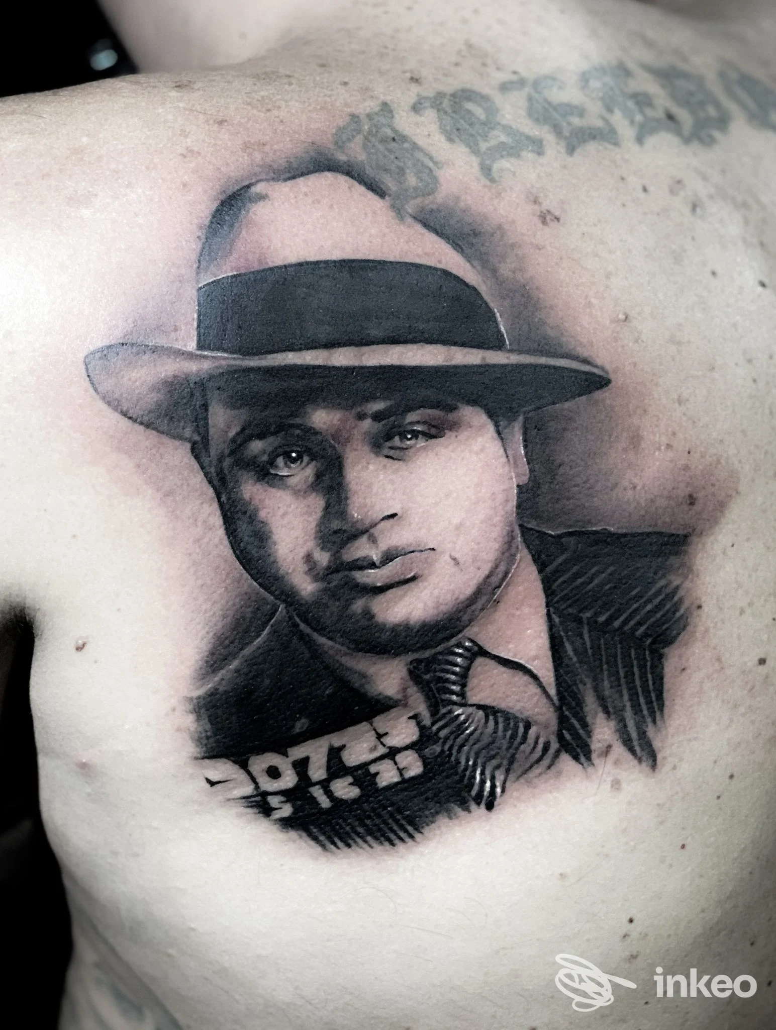 Tattoo realistico in bianco e nero di un uomo con cappello, posto sul torace della persona, realizzato da The Raimondi's General Tattoo a Napoli.