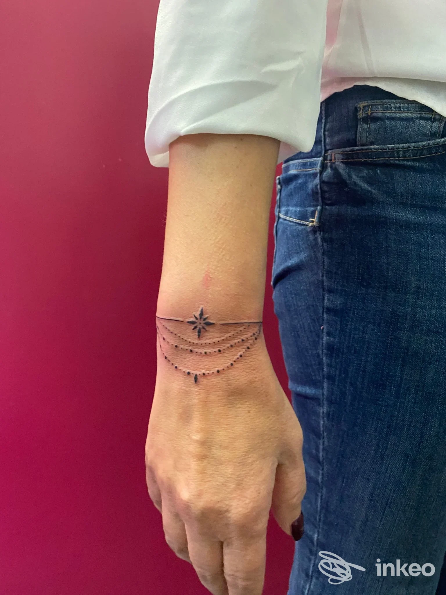 Polso sinistro con tatuaggio sottile a catene e piccole stelle, visibile accanto alla manica della camicia e ai jeans. Firma: Tattoo Ultraviolet, Baronissi.