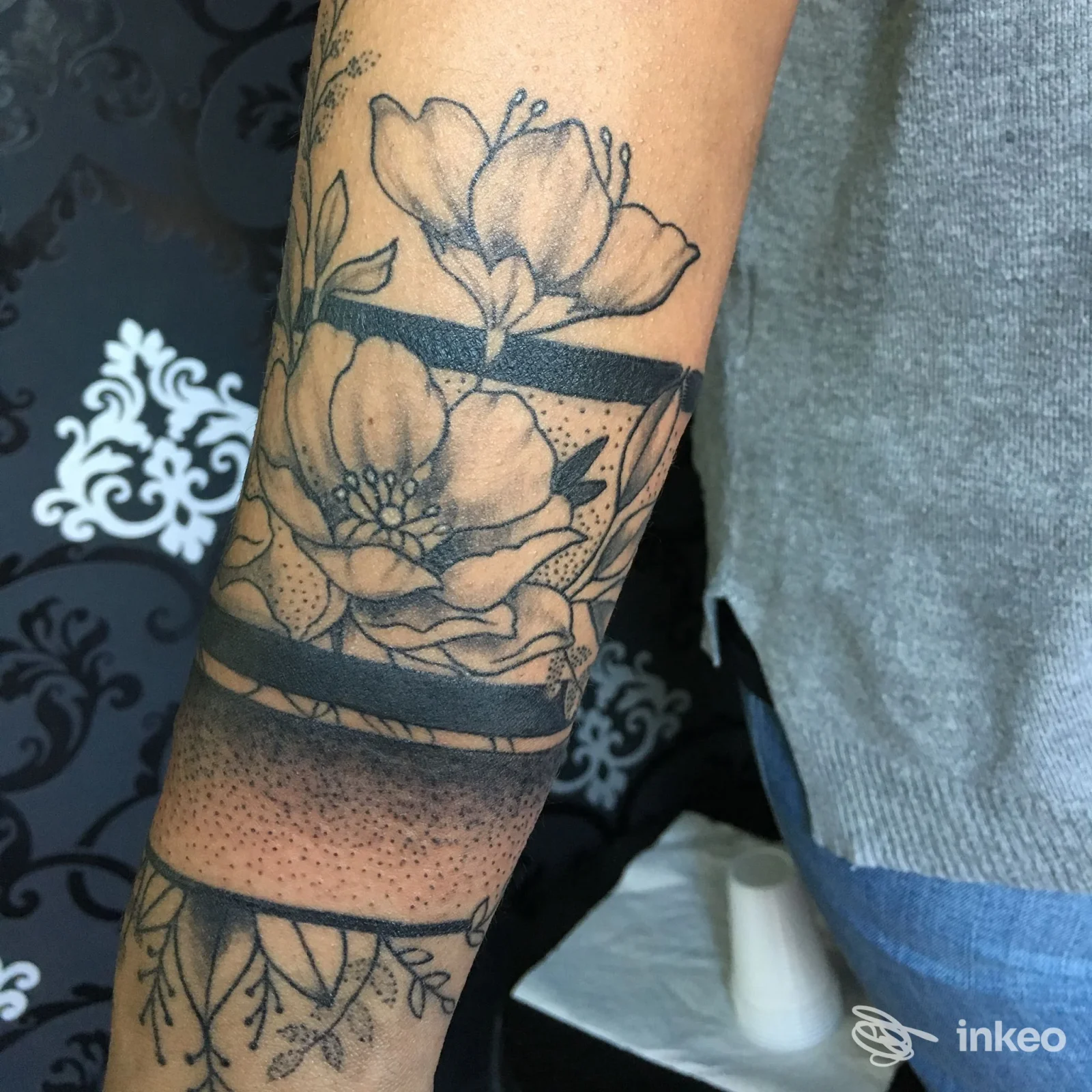 Tattoo floreale nero su pelle del braccio, realizzato in stile linework, visibile sulla parte inferiore del braccio presso Tattoo Ultraviolet a Baronissi.