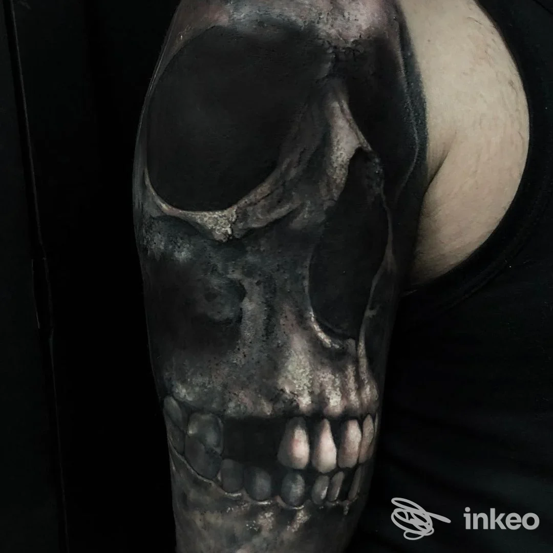 Tattoo realistico di teschio su braccio, tonalità nero-grigio, realizzato sulla pelle.