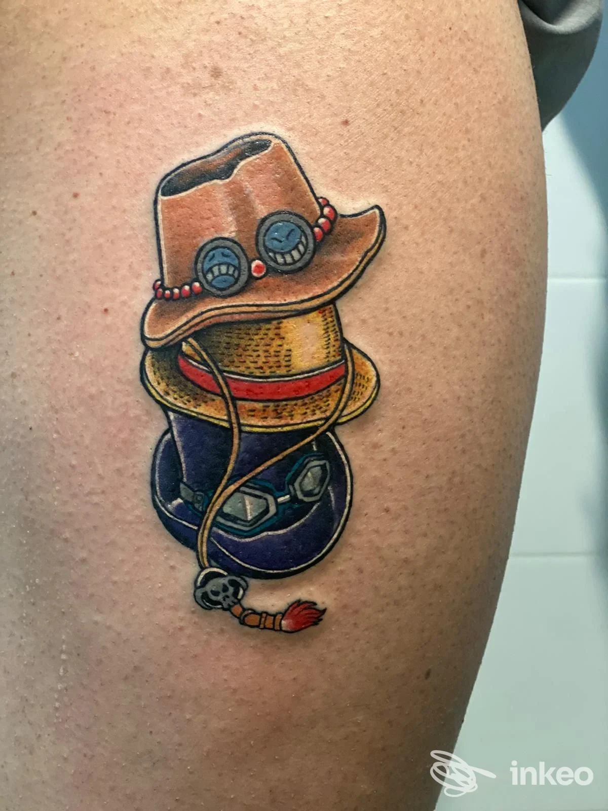 Tattoo colorato su pelle, raffigurante un cappello con lenti e accessori, stile cartone animato, localizzato sulla gamba; firma dello studio Ink Break, Caserta.