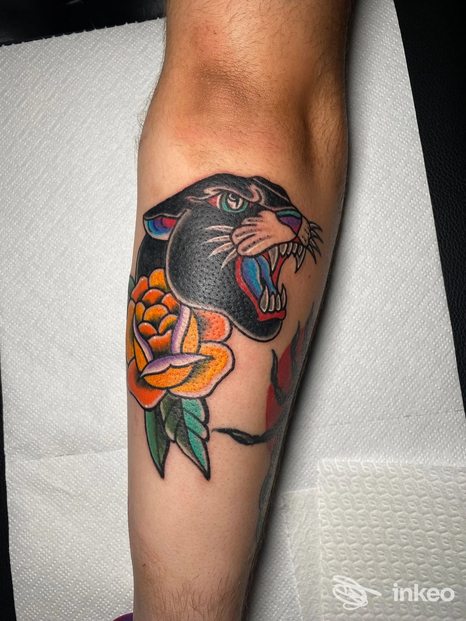 Tatuaggio di serpente nero con fauci aperte e fiori arancioni sull'avambraccio, realizzato nello studio Sailing Ship Tattoo ad Agerola