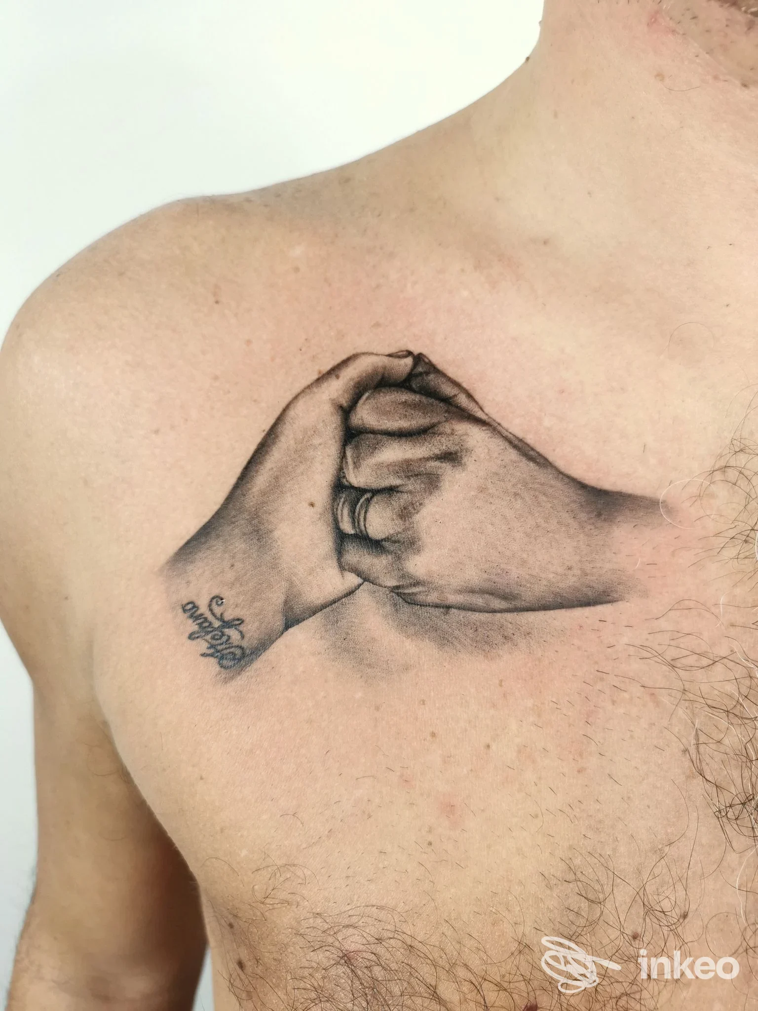 Due mani intrecciate tatuate sul torace, stile realistico in bianco e nero. tatuaggio chiaramente visibile su pelle, nessun viso intero presente.