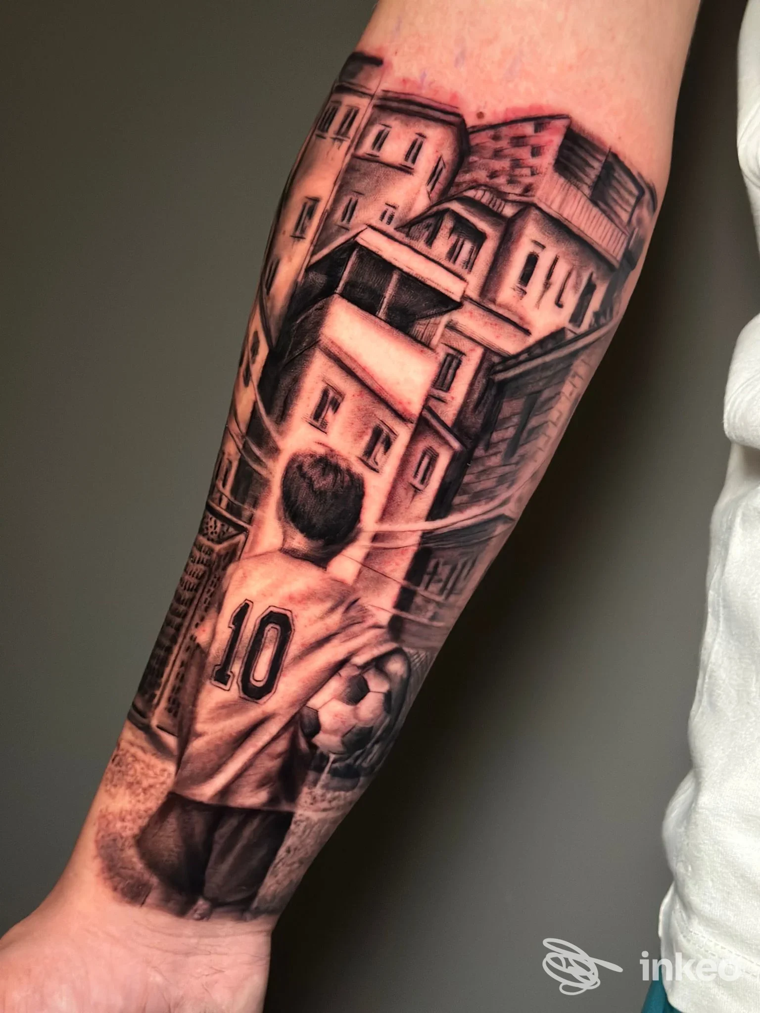 Tattoo realistico sul polso raffigurante un giocatore con maglia numero 10 che guarda un paesaggio urbano, realizzato da Inkorporate Tattoo Shop a Giugliano in Campania.