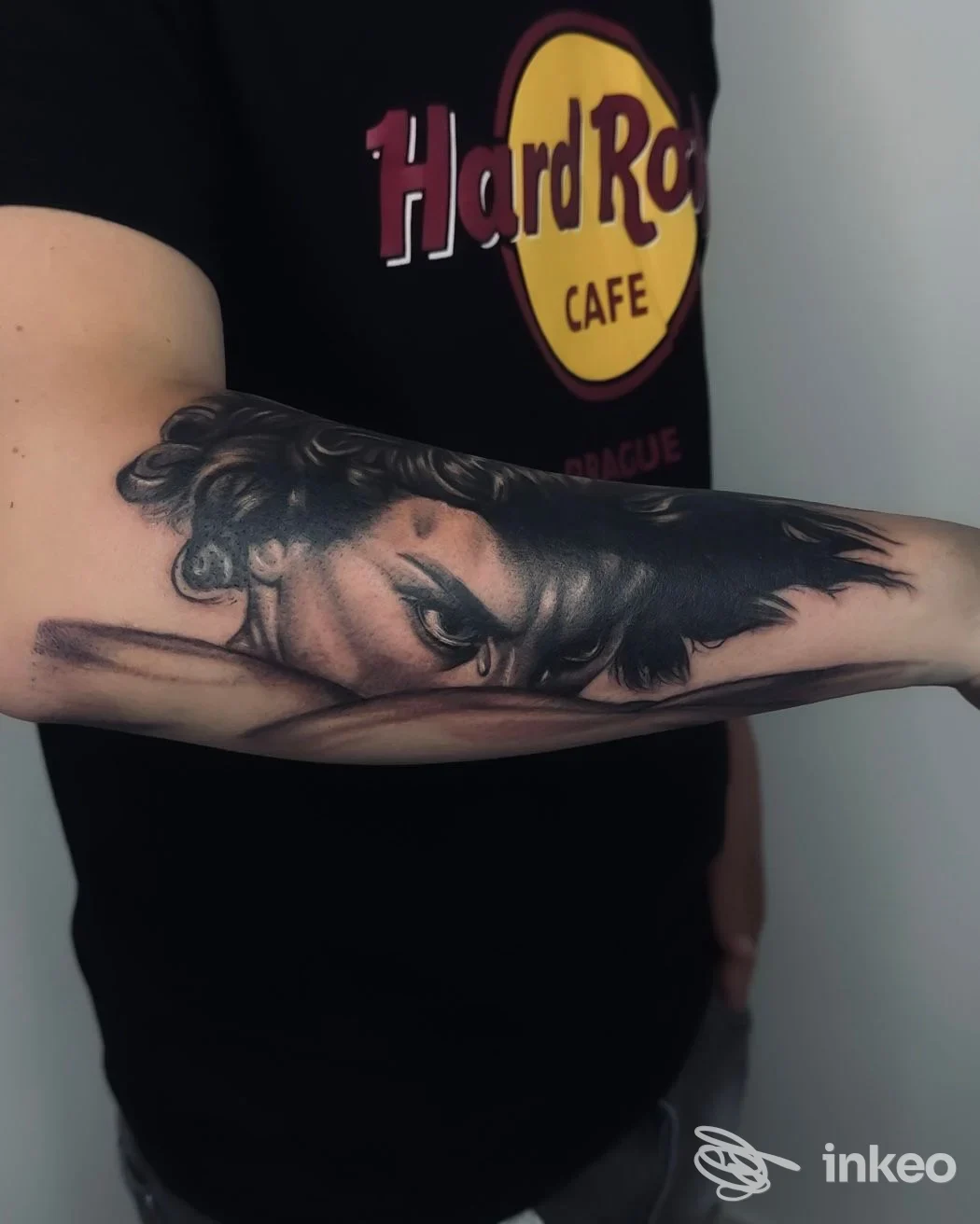Avambraccio di una persona con tatuaggio realistico in bianco e nero che ritrae il volto di una donna, sfumato su pelle, senza elementi di overlay o contenuti digitali.