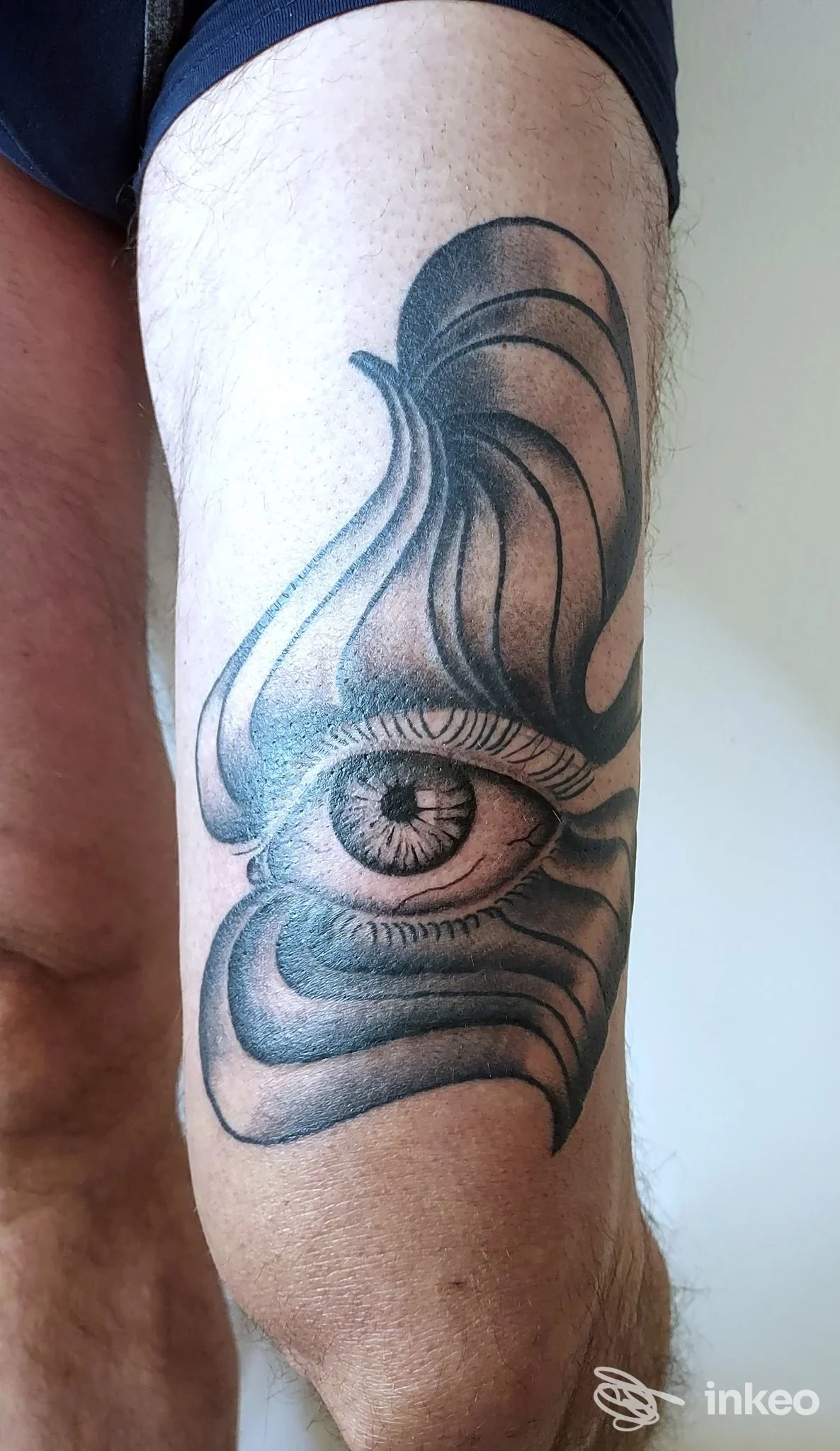 Tattoo all'avambraccio raffigurante un occhio centrale con cornici curve, in bianco e nero, realizzato da Big Eyes Tattoo, citta non fornita.