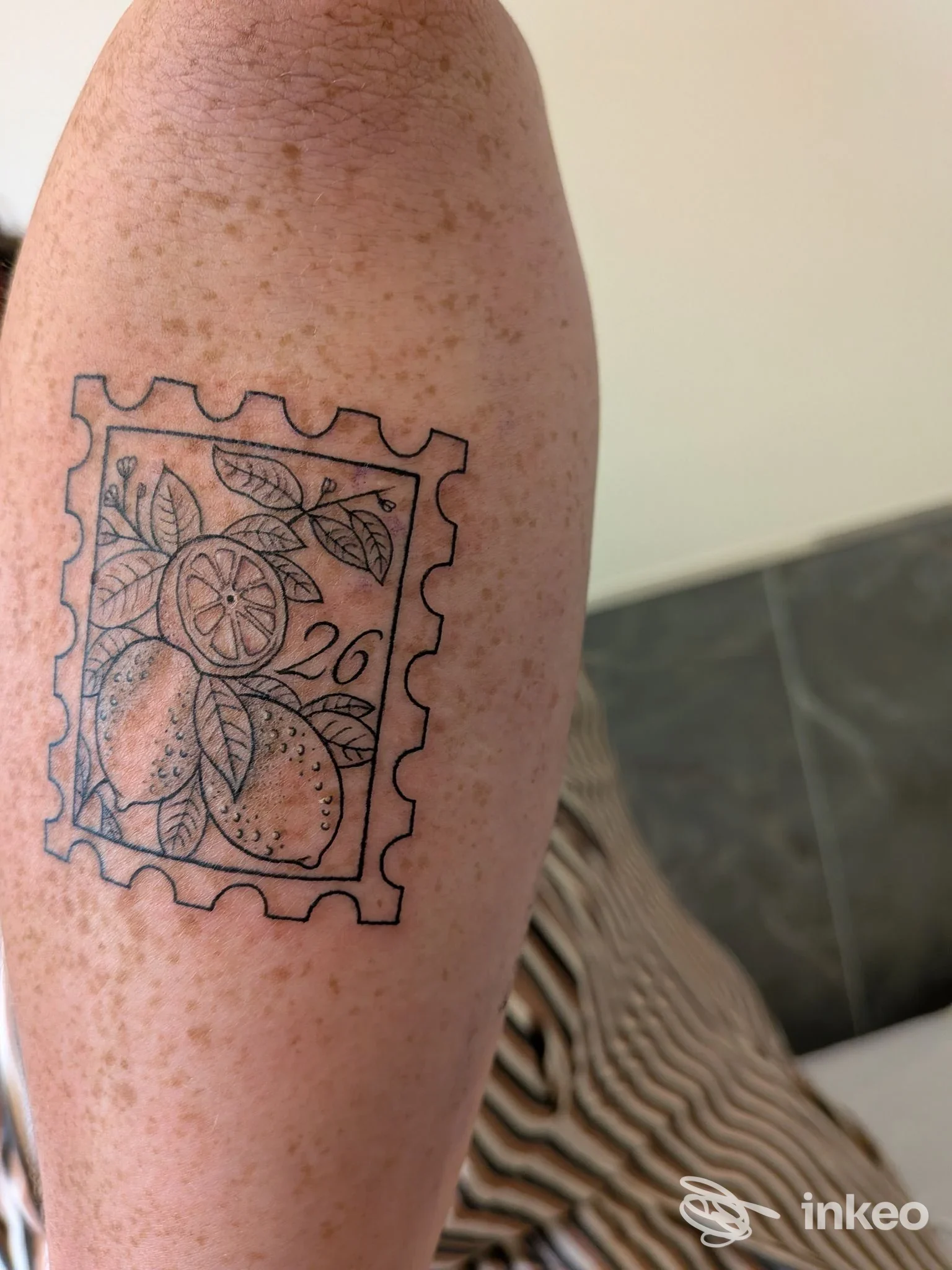 Tatuaggio su avambraccio raffigurante un timbro con arance e foglie realizzato su pelle, eseguito nello studio Asso Tattoo Napoli, Napoli.