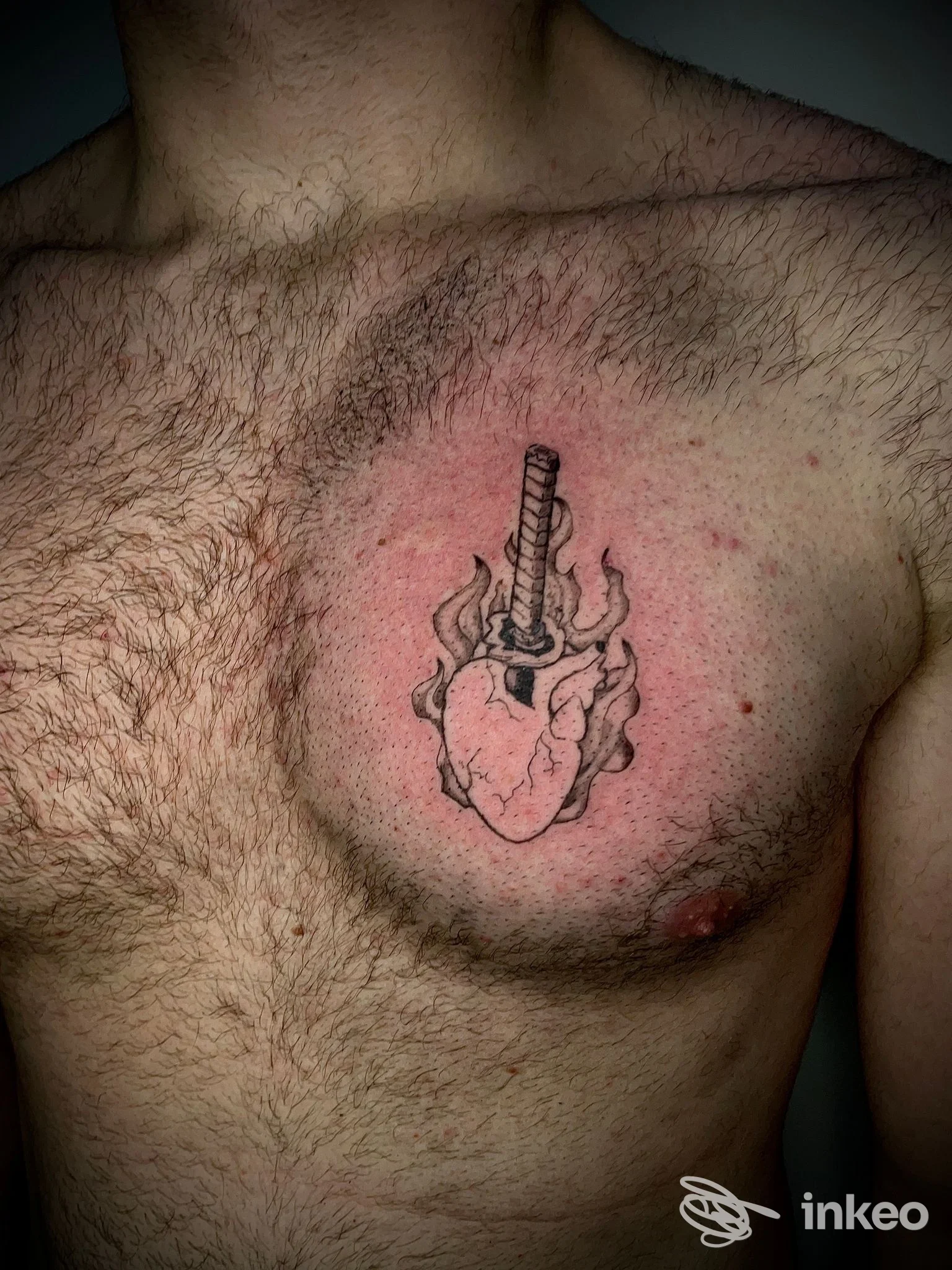 Tattoo realistico sul torace di uomo, raffigurante cuore umano con spada, contorno pelle chiara, peli sul petto, tonalità rosse attorno all’area tatuata; studio Vault 42 Tattoo, Battipaglia.