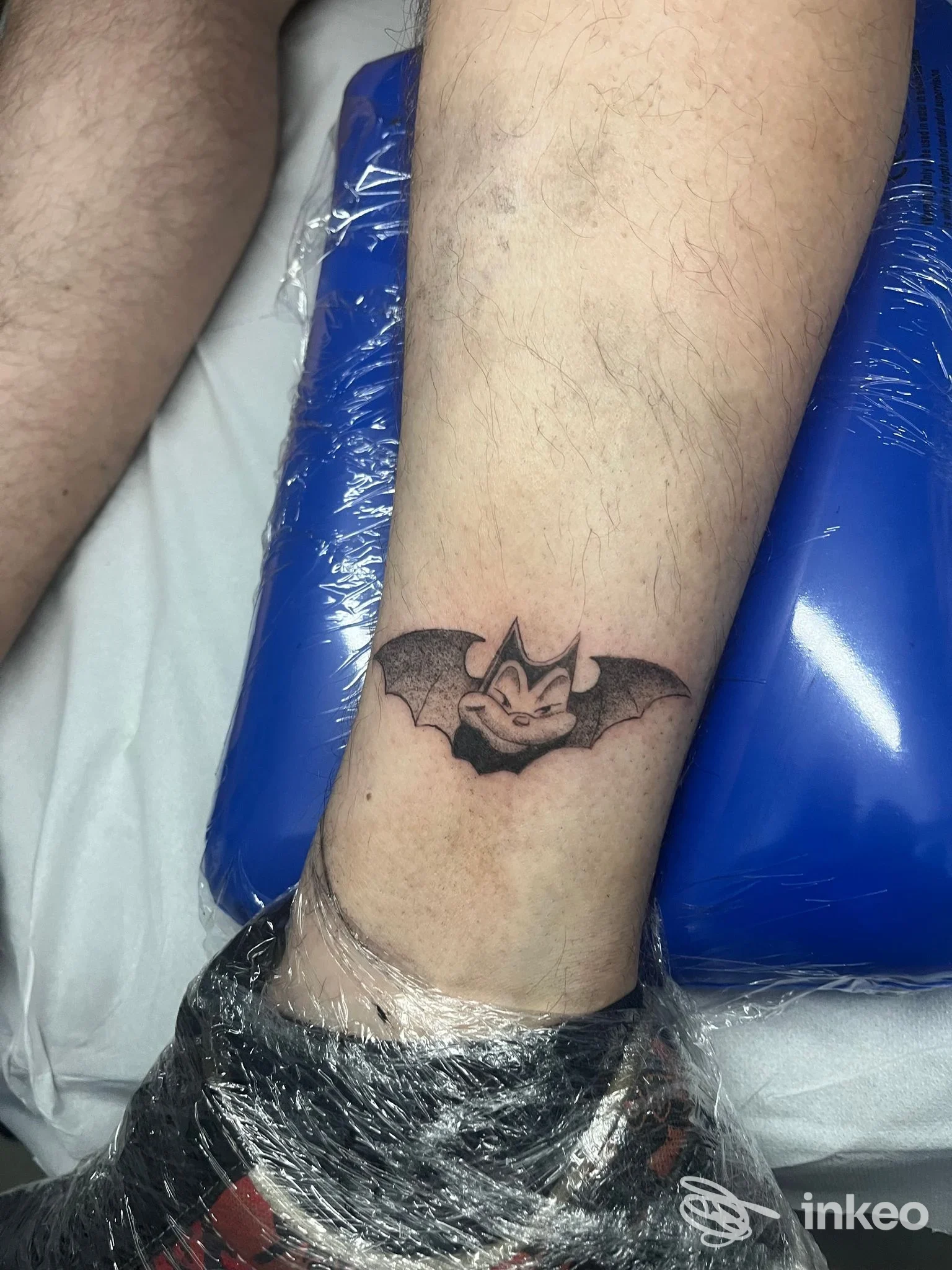 Tattoo nero di un pipistrello sul polpaccio di una persona, contorni netti e riempimento scuro, senza volto visibile nell’immagine.