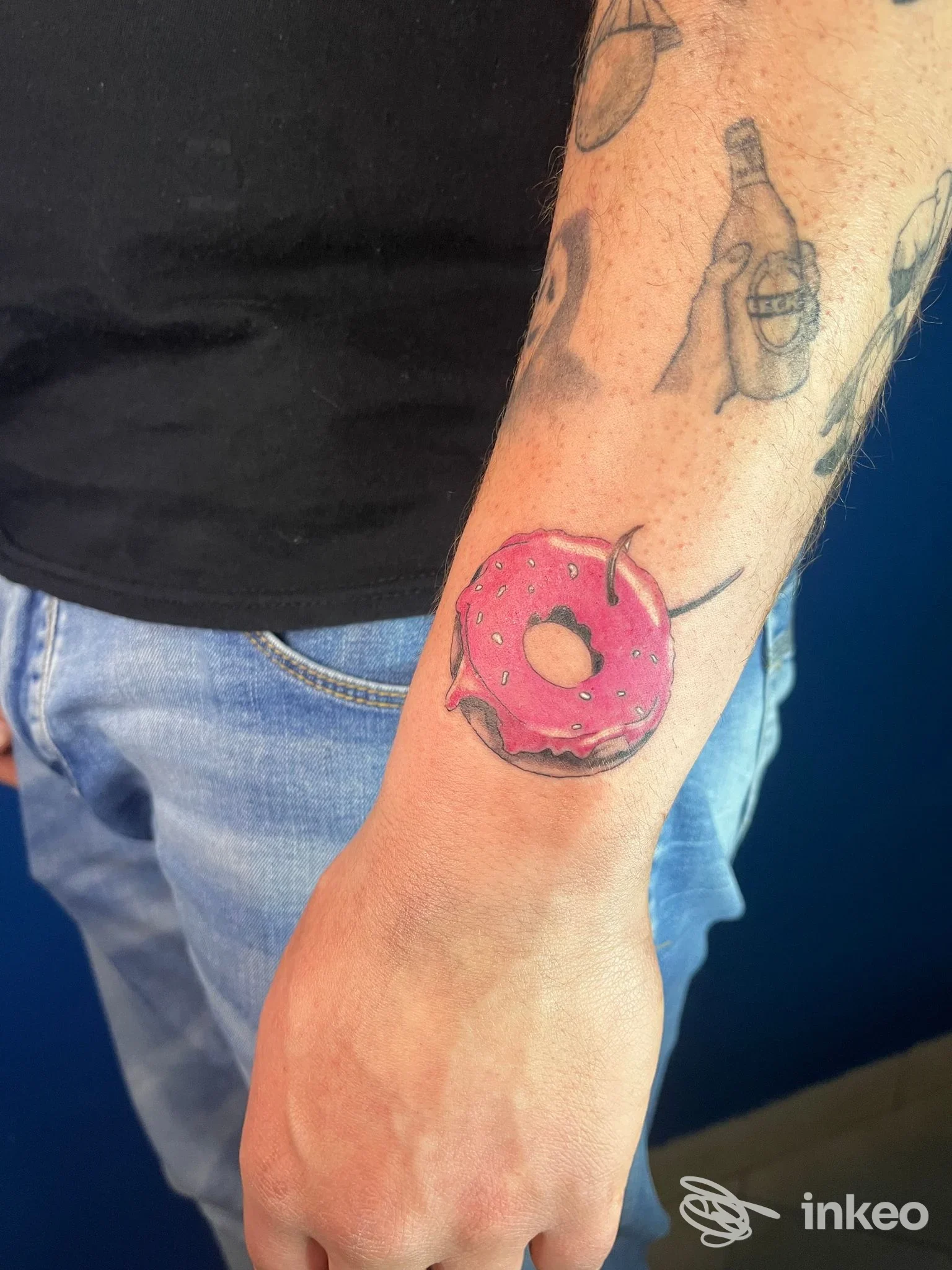 Avambraccio di un uomo con un tatuaggio visibile di una ciambella rosa con glassa, sul polso destro. Studio Vault 42 Tattoo, Battipaglia.