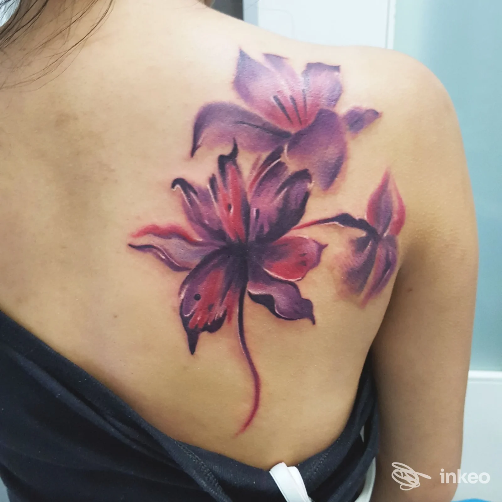 Tatuaggio floreale viola e rosa sulla spalla di una persona, realizzato da Agon Tattoo SAS a San Nicola La Strada.