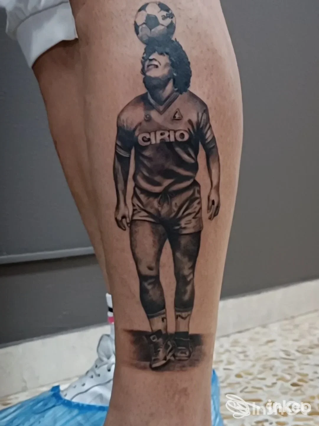 Tattoo raffigurante un calciatore su gamba, con pallone in testa, indossando uniforme vintage; lato anteriore della gamba destra visibile, sfondo neutro.