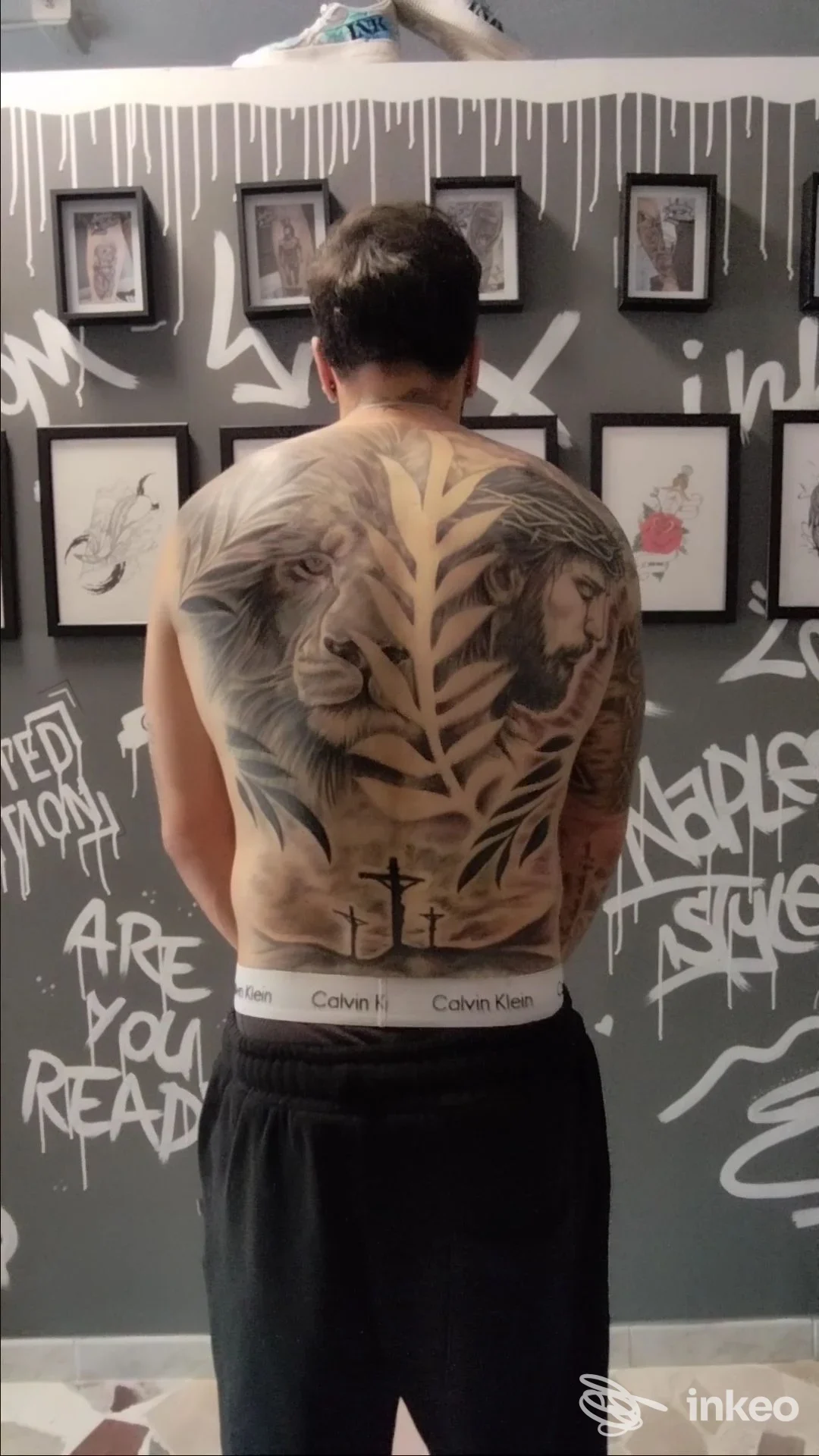 Tattoo sulla schiena di un uomo, disegno grande e coprente con figure leonine e motivo a foglie, sfondo studio Modena presso Andrestattoo Passion Studio, cintura Calvin Klein visibile.