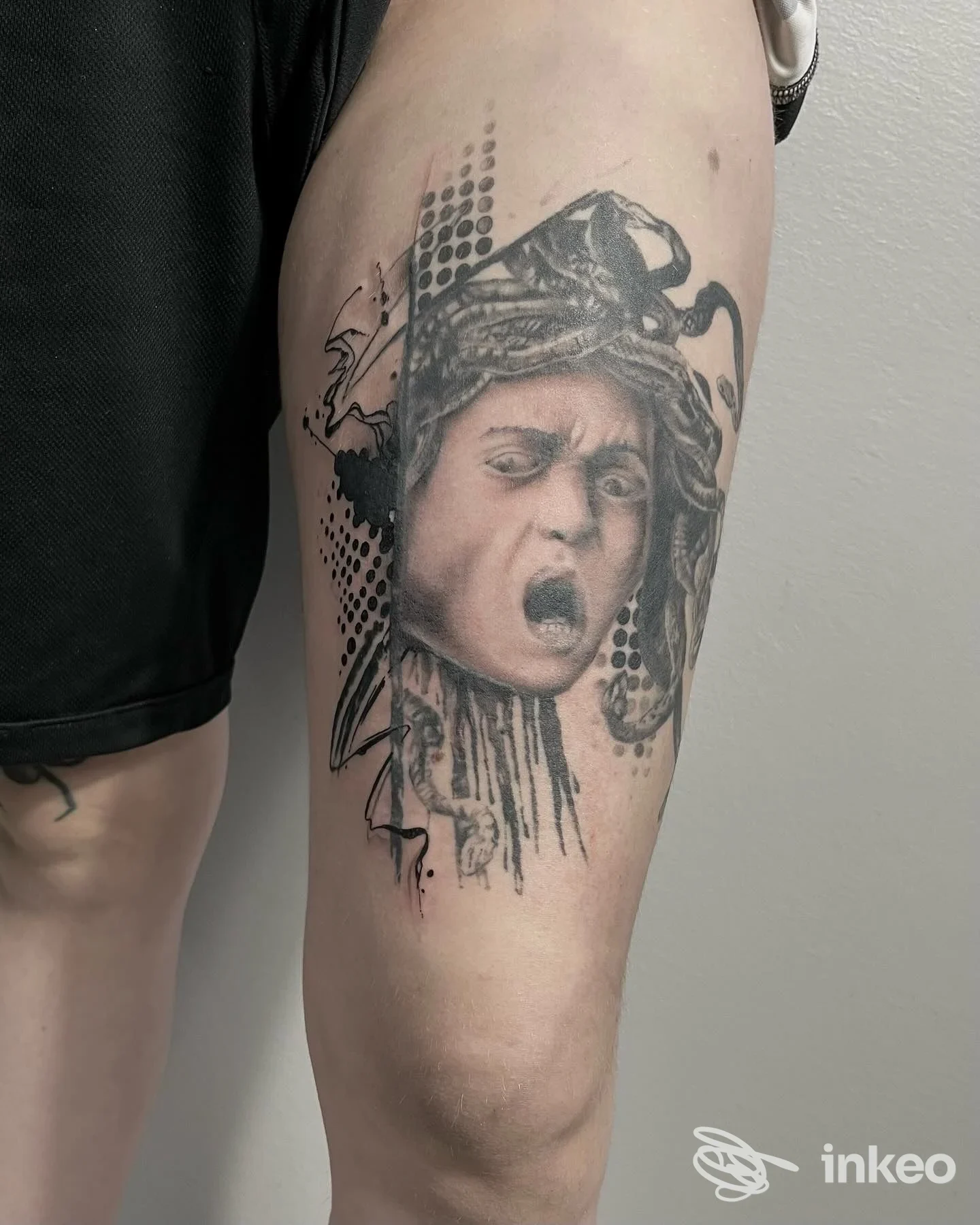Tattoo realistico su avambraccio raffigurante una testa espressiva con cappuccio, realizzata sulla pelle e chiaramente visibile in primo piano.