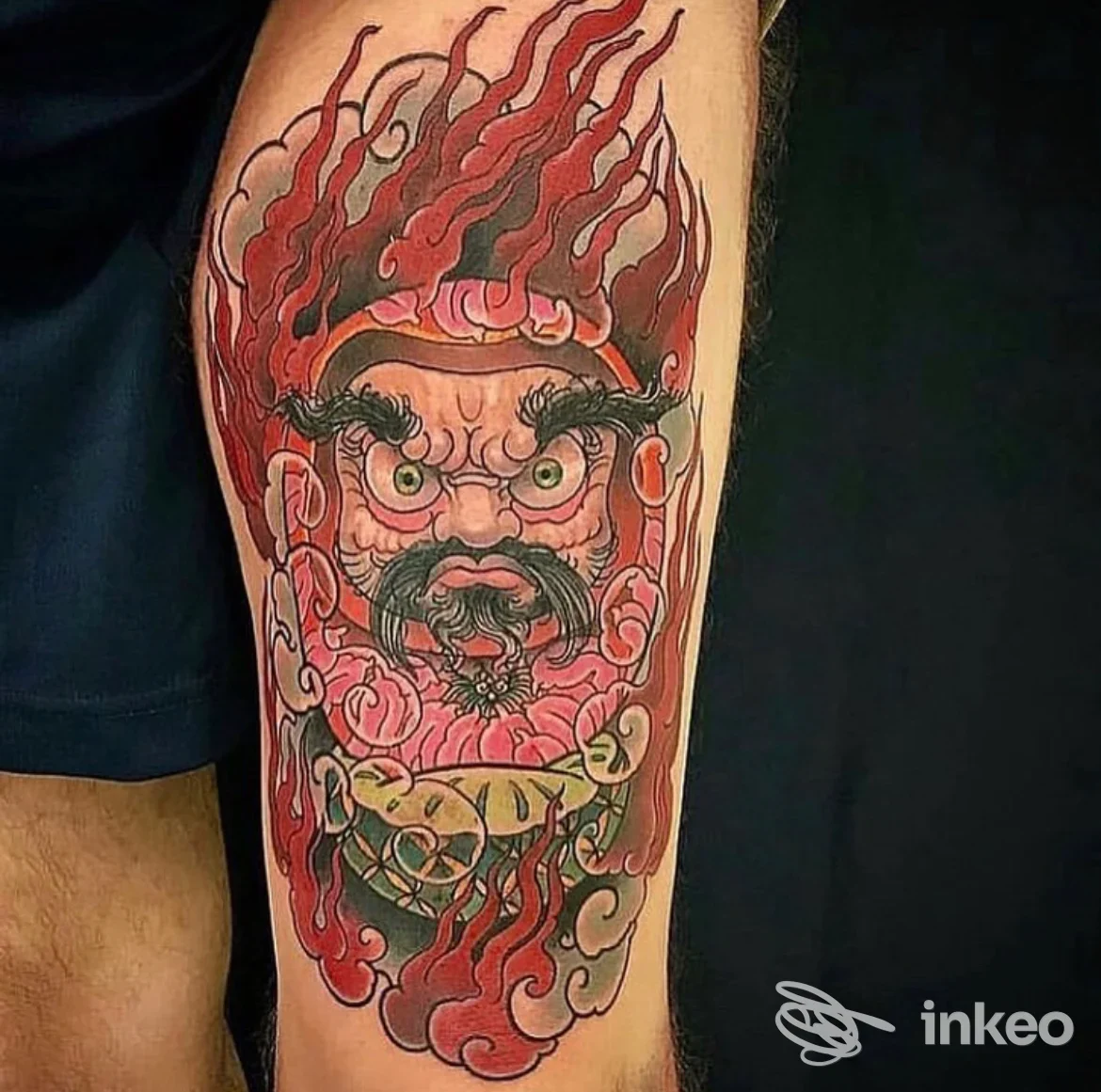 Tattoo sull’avambraccio raffigurante una figura demonica con fuoco rosso intorno, colori vividi e contorni definiti.