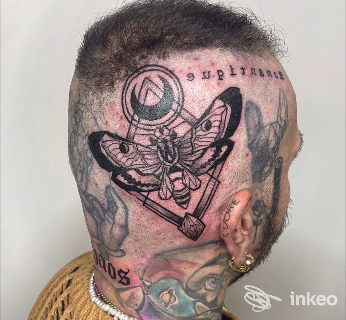 Tattoo reale sulla testa di una persona: design con farfalla e elementi geometrici, visibile insieme agli altri tatuaggi sul collo, senza overlay social o immagine di schermo.
