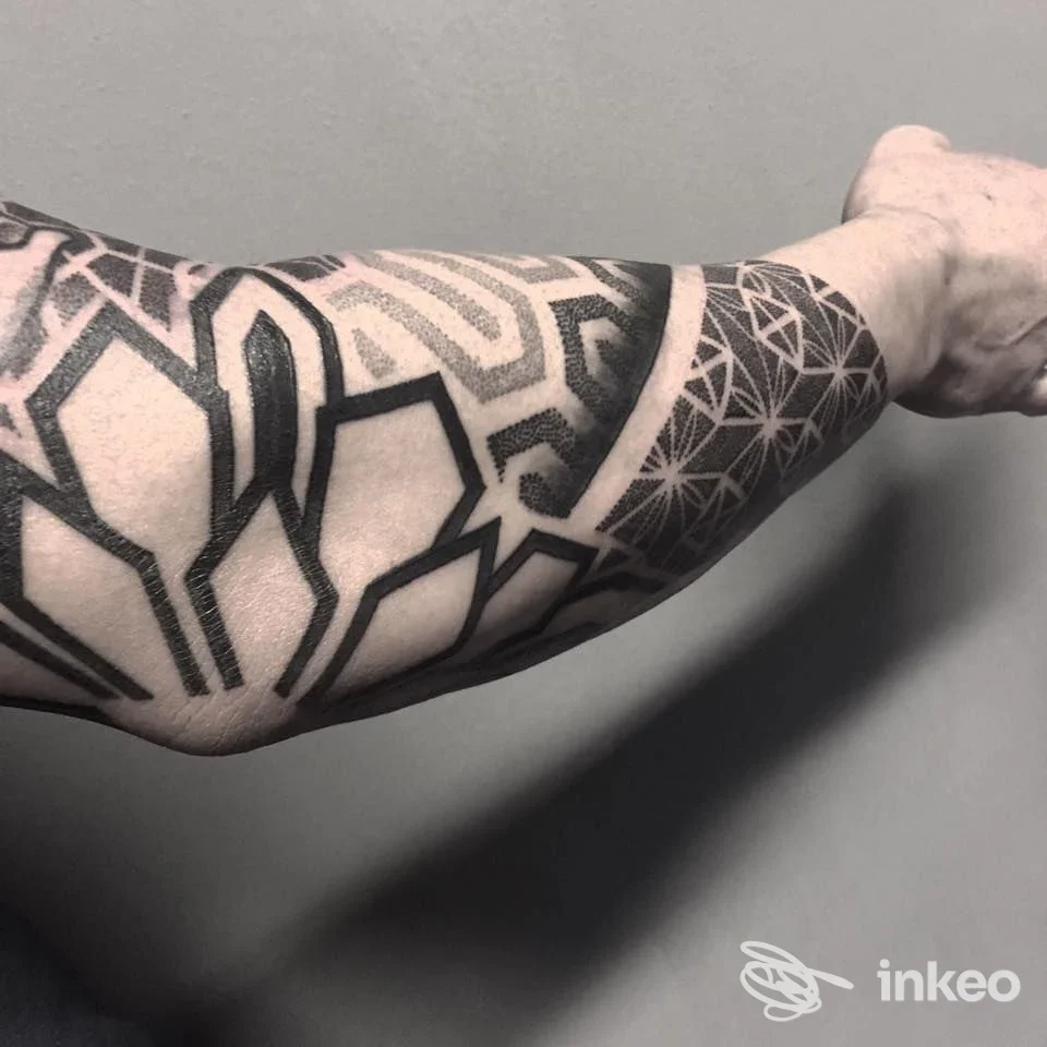 Tattoo geometrico in nero sull’avambraccio visibile, stile lineare, realizzato sulla pelle umana; immagine scattata in Riccione nello studio INKdustria Tattoo.