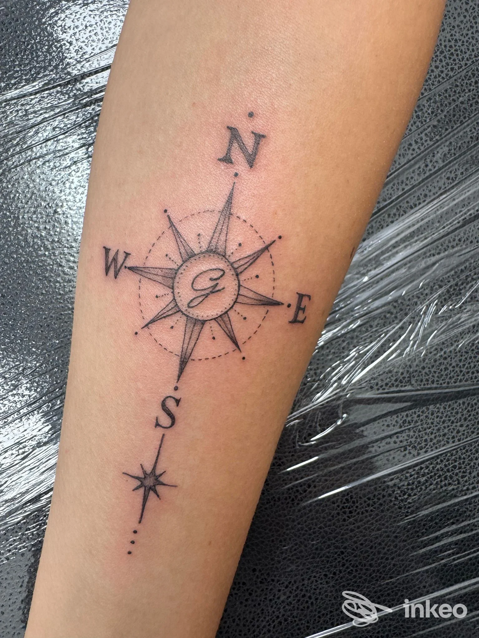 Tatuaggio a bussola su avambraccio, con bussole e punti cardinali nitidi, realizzato sulla pelle.
