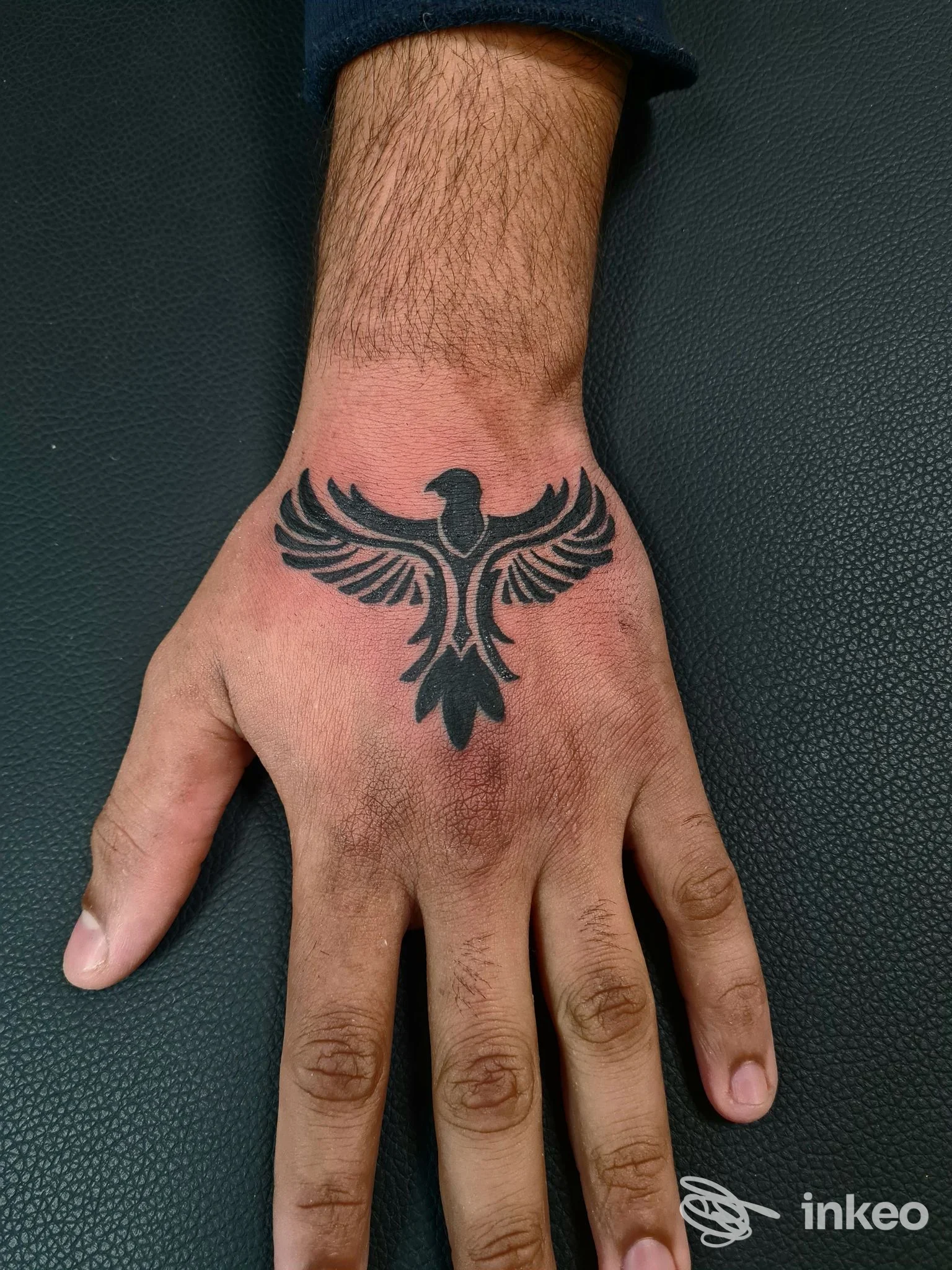 Tattoo sul dorso della mano raffigurante un uccello stilizzato, eseguito su un paziente; studio History of my Skin Tattoo Studio, Fidenza.