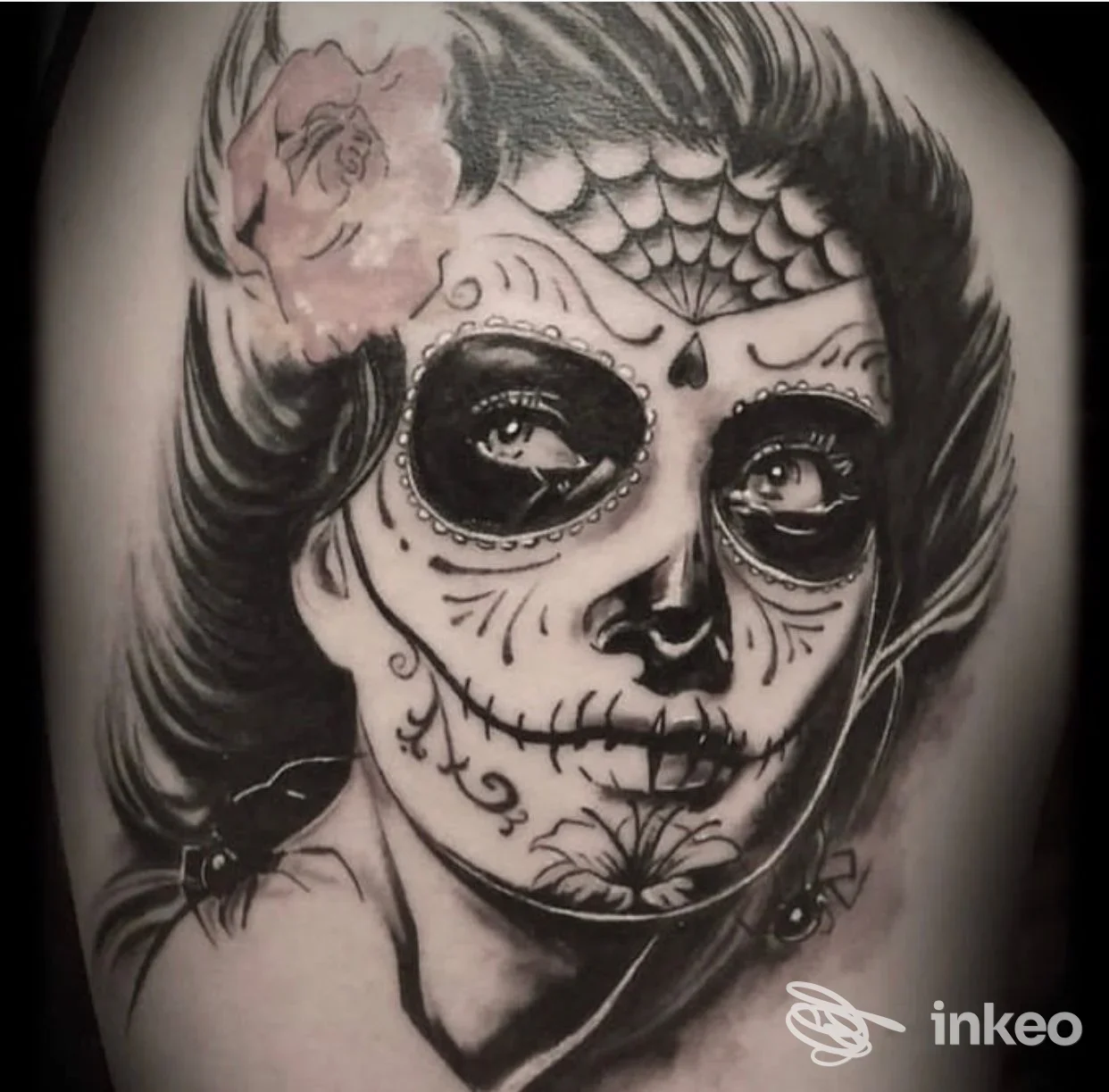 Tatuaggio realistico in bianco e nero su pelle raffigurante una testa di sugar skull, con contorni e sfumature dettagliate visibile sul braccio.