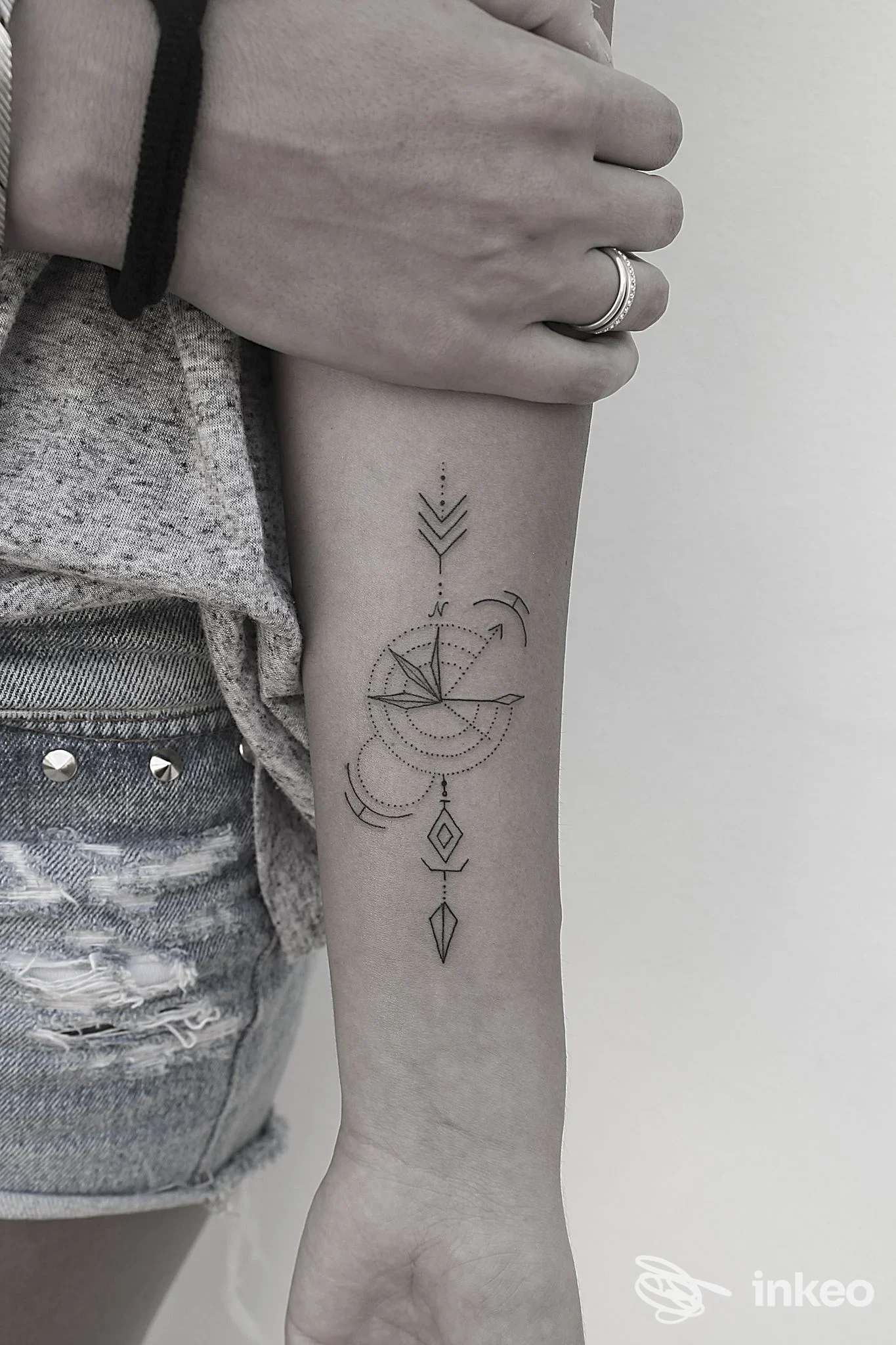 Tattoo geometrico verticale sull'avambraccio, linee sottili, cerchi parziali e ornamenti a diamante; realizzato sulla pelle, senza volto visibile, in Riccione presso Carloxid Tattoo.