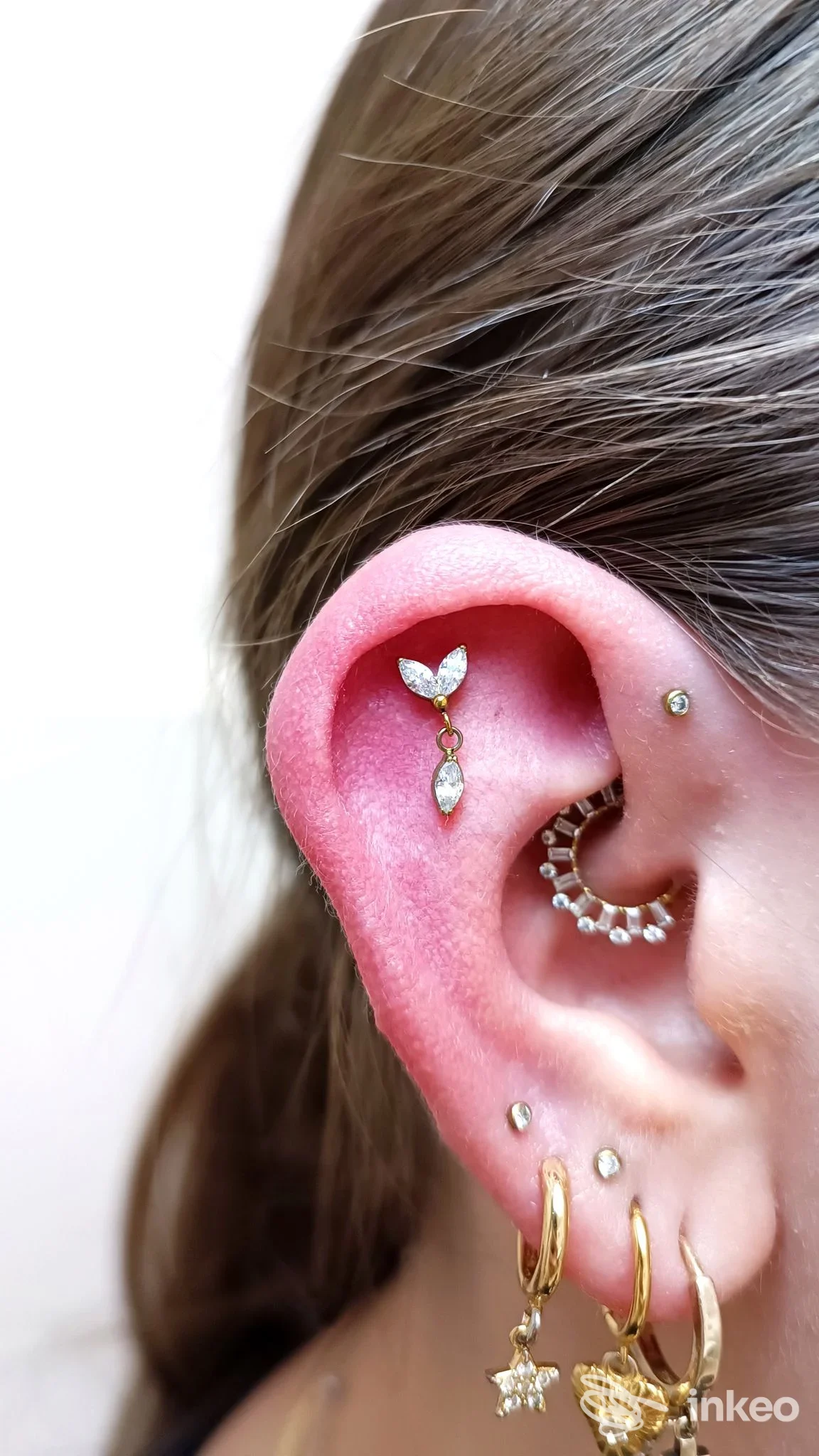 Primo piano di un orecchio con diversi piercing elegantemente posizionati, foto fornita da Trippy Piercing, San Pietro in Casale.
