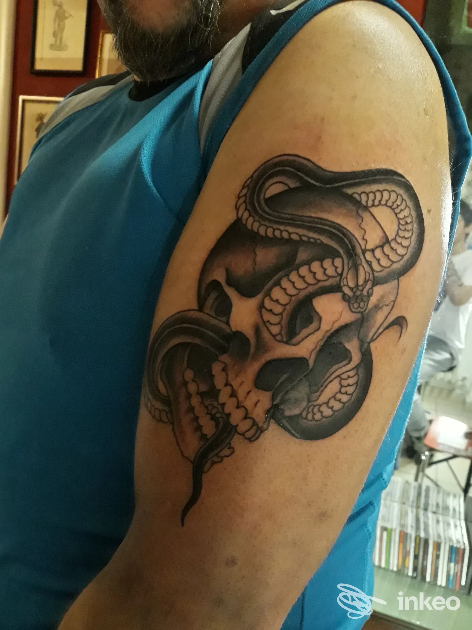 Tatuaggio su braccio di serpente e teschio, eseguito sulla pelle di un uomo, sfondo da studio.