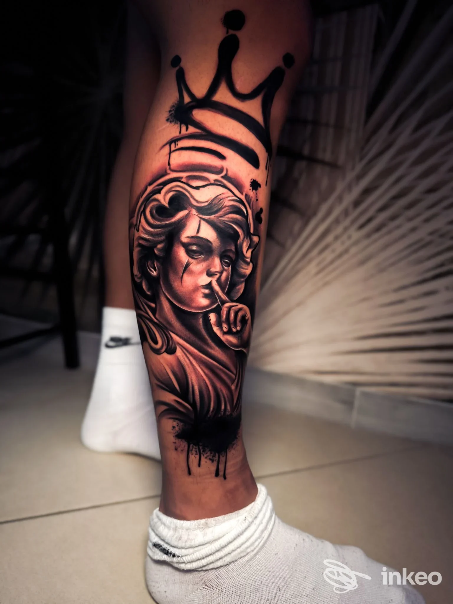 Tattoo realistico su gamba sinistra: ritratto femminile in bianco e nero con corona sopra, realizzato su pelle nuda.