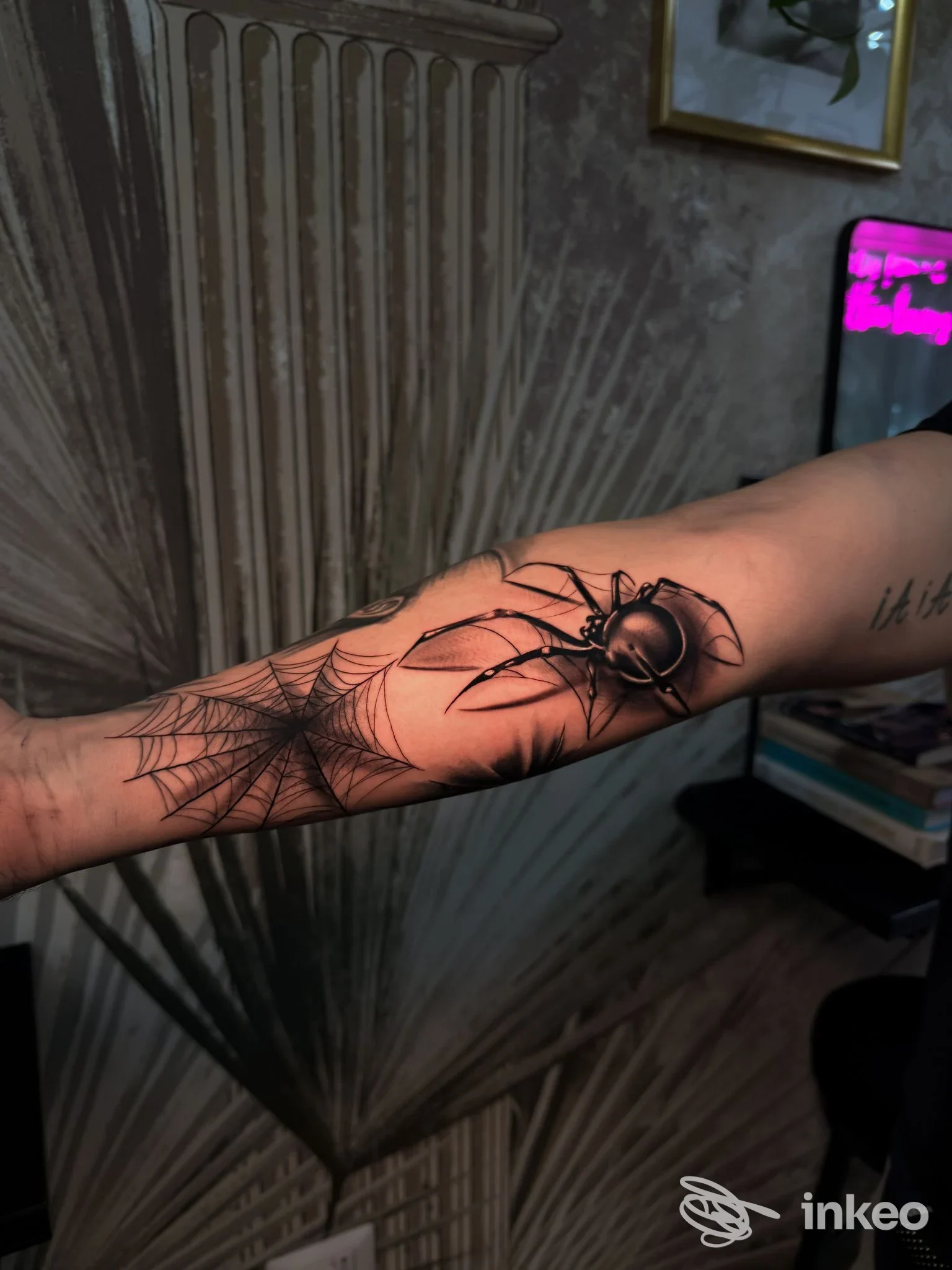 Tattoo realistico di ragno e ragnatela sull’avambraccio, senza volti visibili né elementi di social media; realizzato su pelle in un ambiente interno.