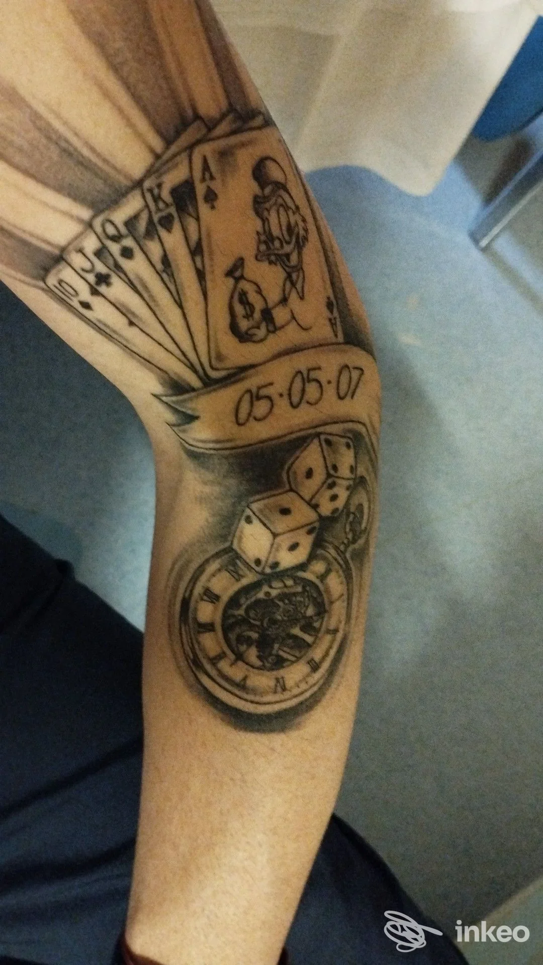 Tattoo sul braccio sinistro raffigurante carte da gioco, dadi e orologio. Non si vedono volti completi. Luogo Parma, Old Roger Tattoo Studio.