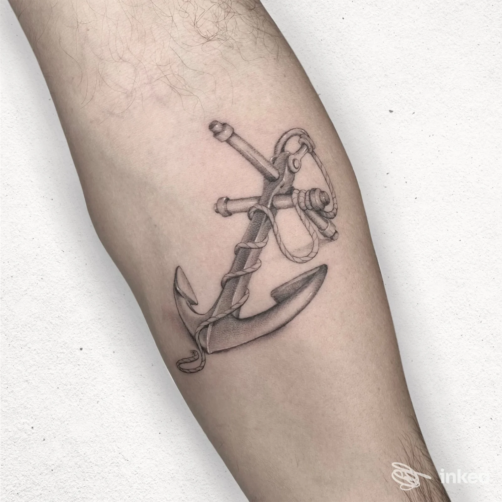 Tattoo sull'avambraccio raffigurante un'ancora intrecciata a una corda, realizzato direttamente sulla pelle, senza volto visibile.