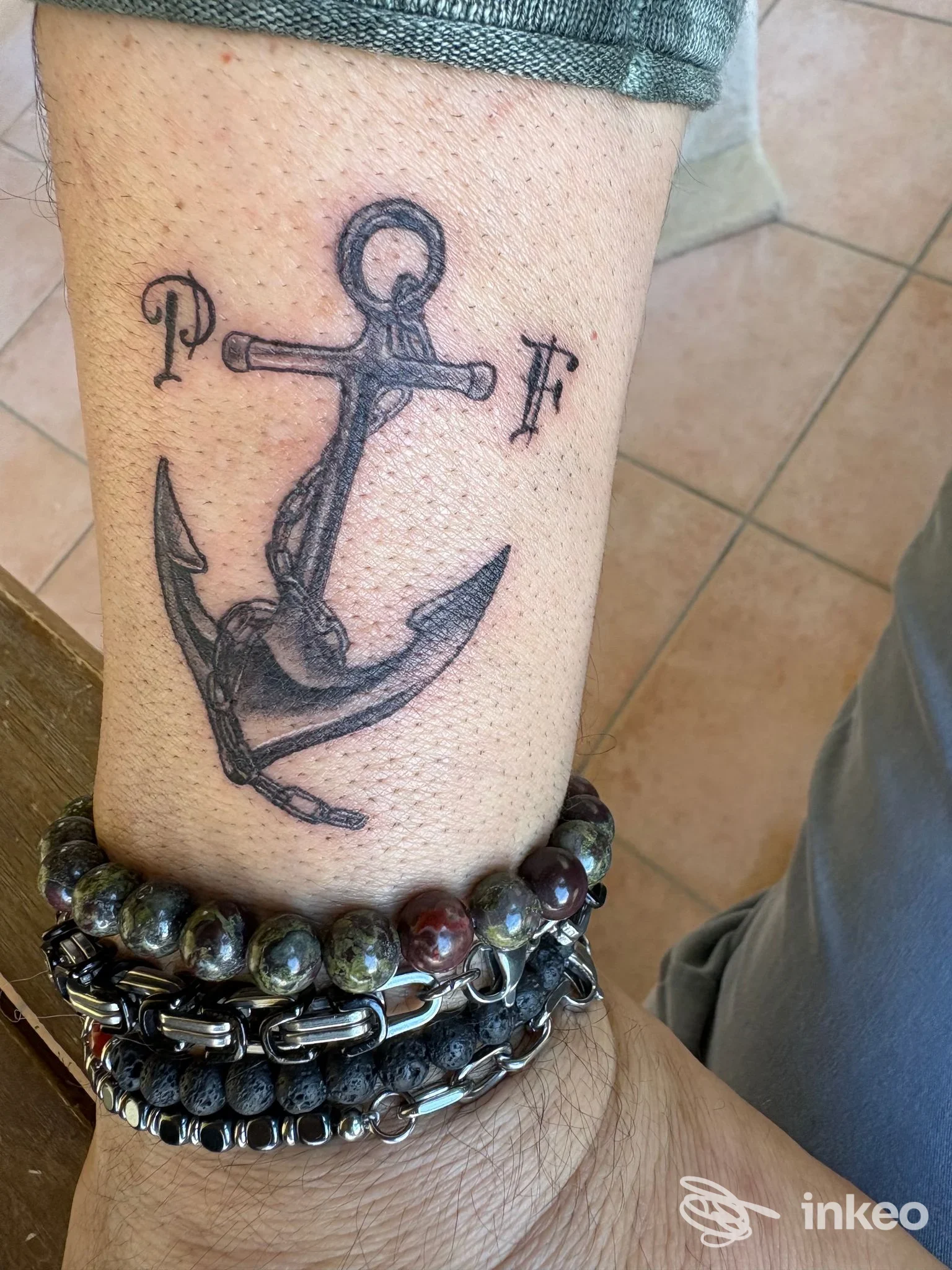 Tatuaggio ad ancora sulla pelle della gamba, con lettere ai lati, realizzato dallo studio Sabry Cobra Tattoo Studio a Vergato.