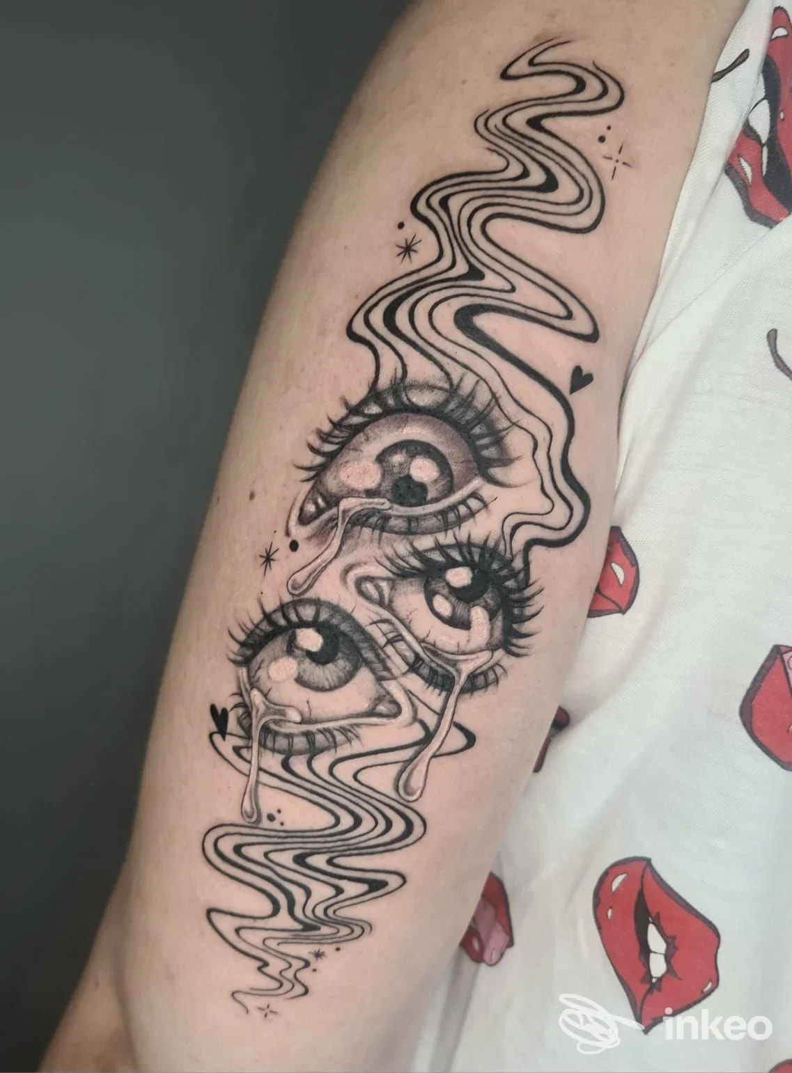 Tatuaggio sul braccio raffigurante tre occhi con ciglia e lacrime, linee curve stilizzate, contorni netti. Studio La Bottega Artigiana del Tatuaggio, Morciano di Romagna.