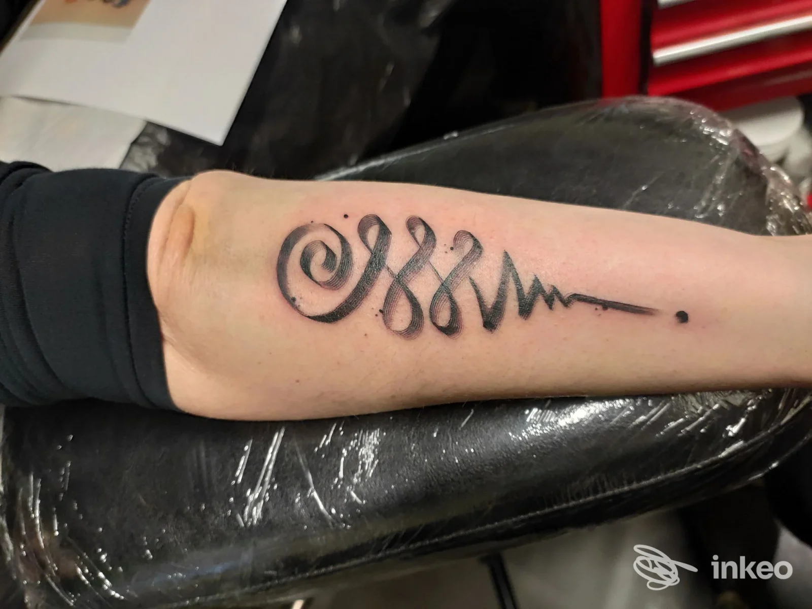 Tattoo sull'avambraccio con spirale nera e linea ondulata, realizzata sulla pelle; studio Alle Tattoo a Limidi.