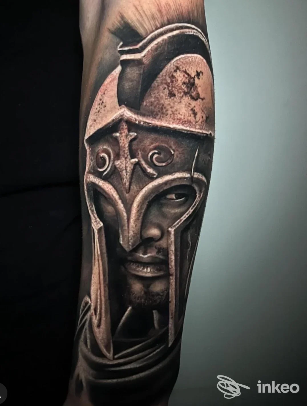Tattoo realistico di un guerriero con elmo su braccio, tonalità scure e dettagli definiti.