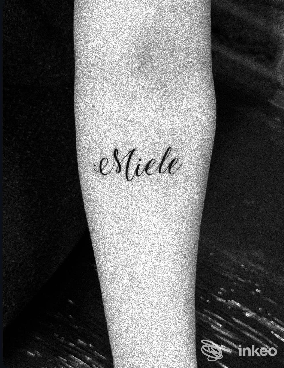 Avambraccio con tatuaggio in corsivo nero che legge 'Miele'