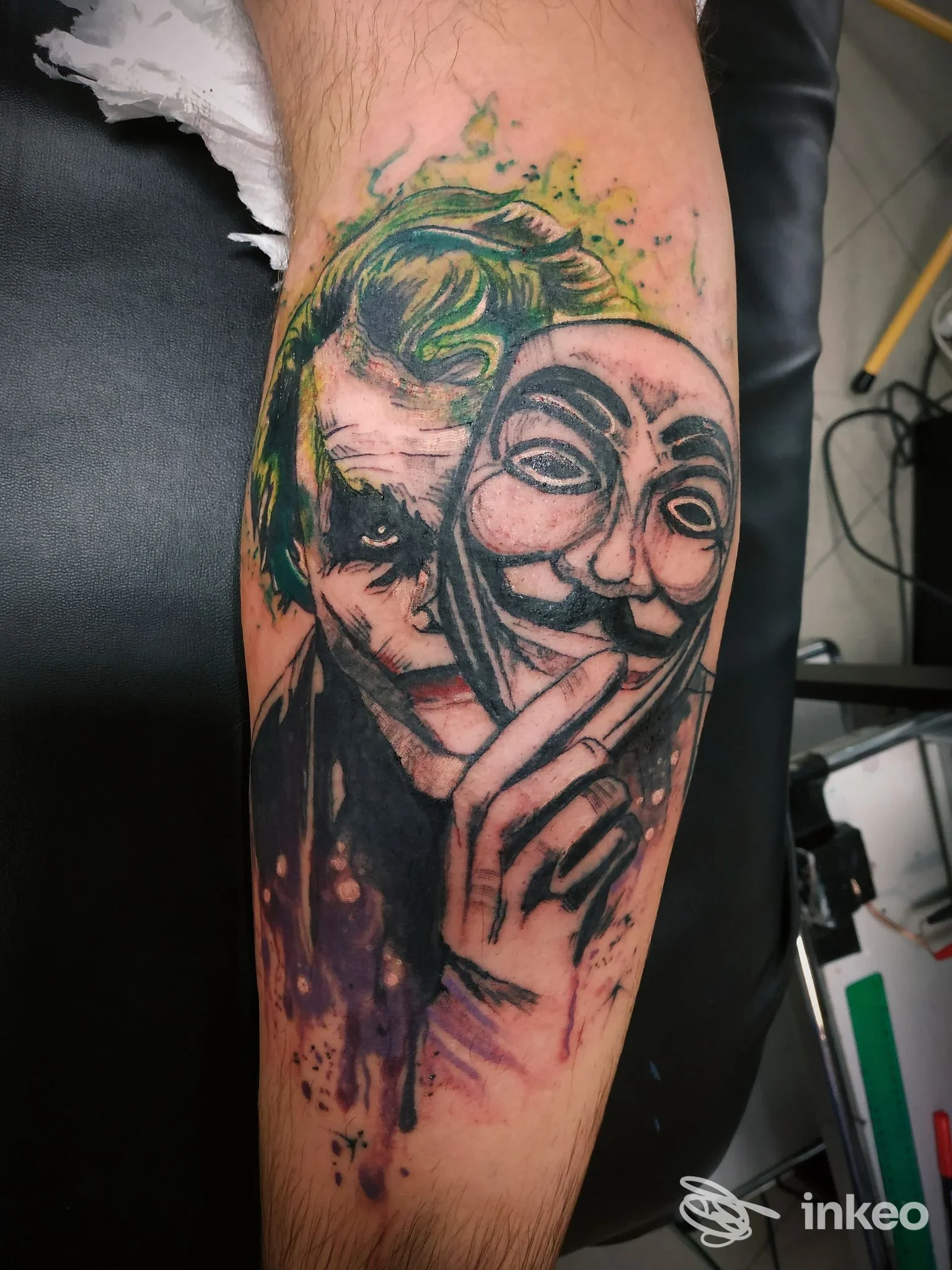 Tatuaggio realistico su avambraccio con volto in stile Joker che tiene una maschera, Inks And Dreams Tattoo Studio, Modena.