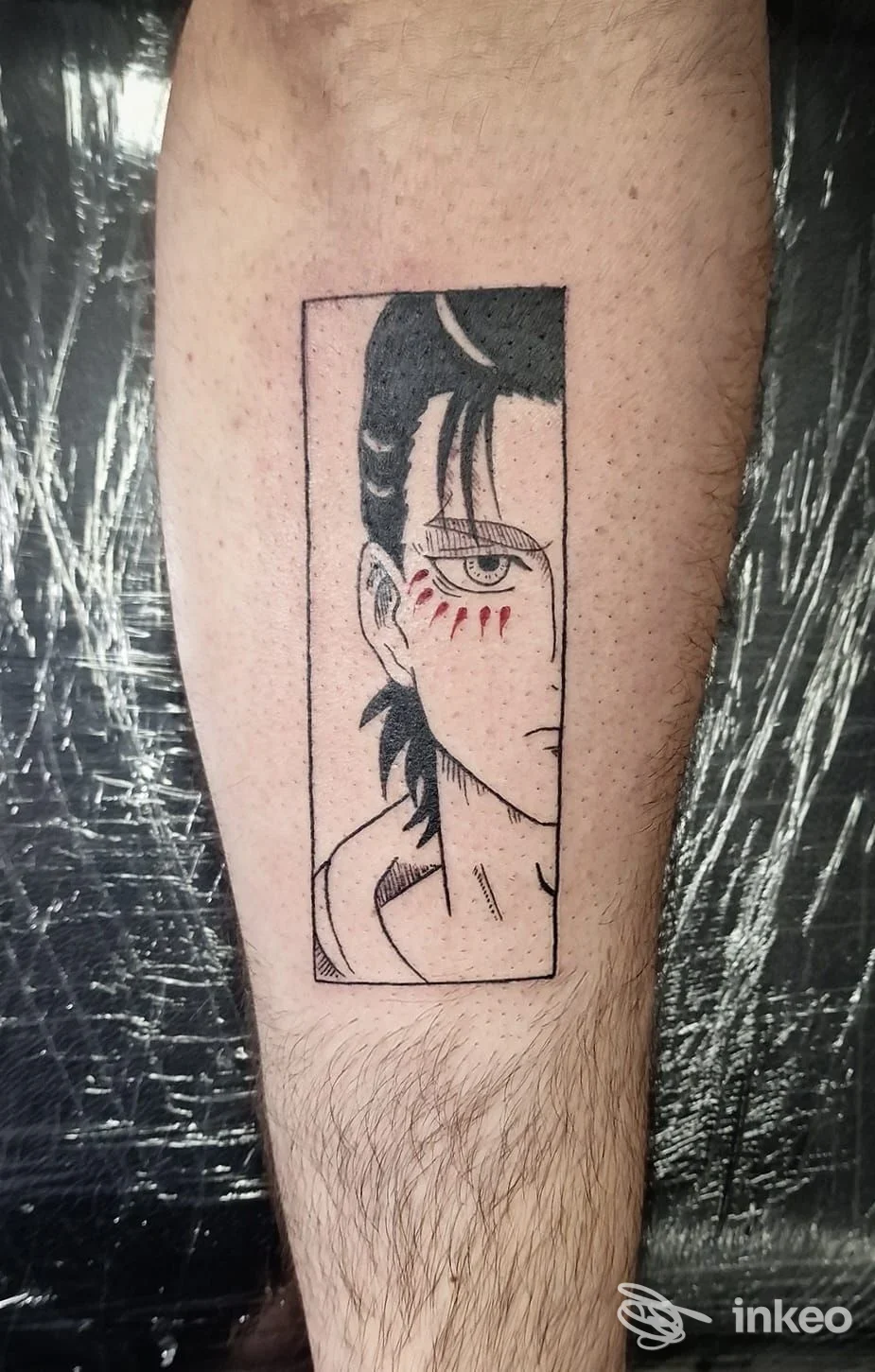 Tatuaggio stilizzato in bianco e nero su polpaccio, volto riquadrato con segni rossi sotto l'occhio. Migart tattoo, Reggio Emilia.