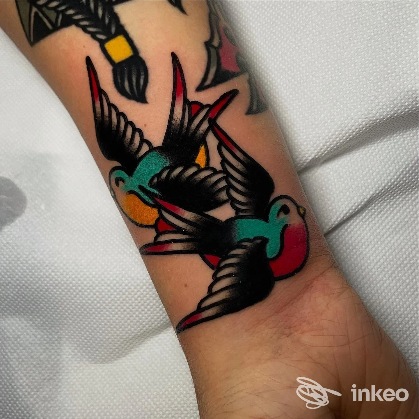 Foto di tatuaggio su polso/avambraccio con due rondini colorate, scattata presso True Love Ink a Fidenza.