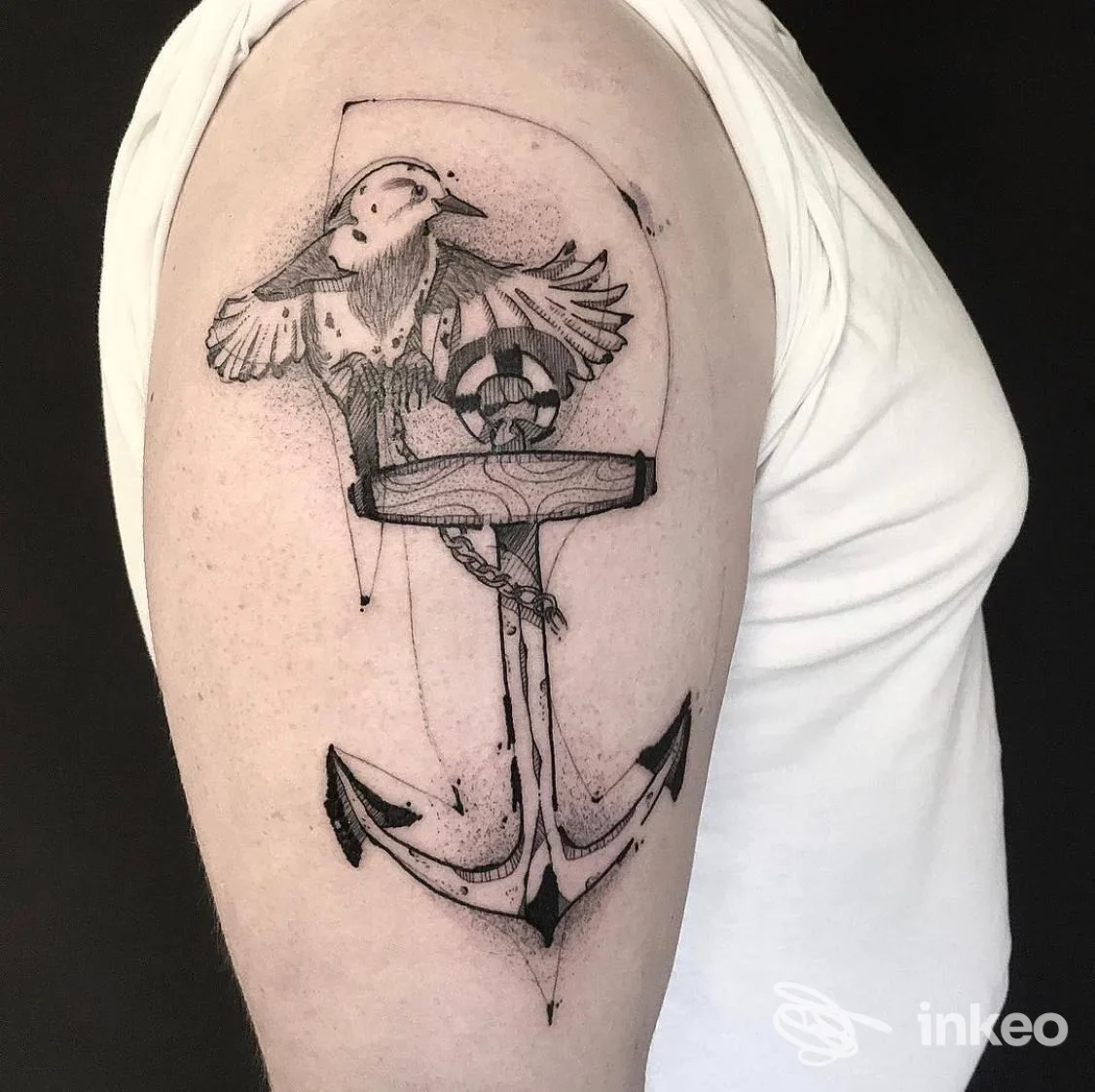 Tatuaggio a inchiostro nero su spalla con ancora stilizzata e uccello, foto fornita da Altra Arte Tatuaggi, Faenza.