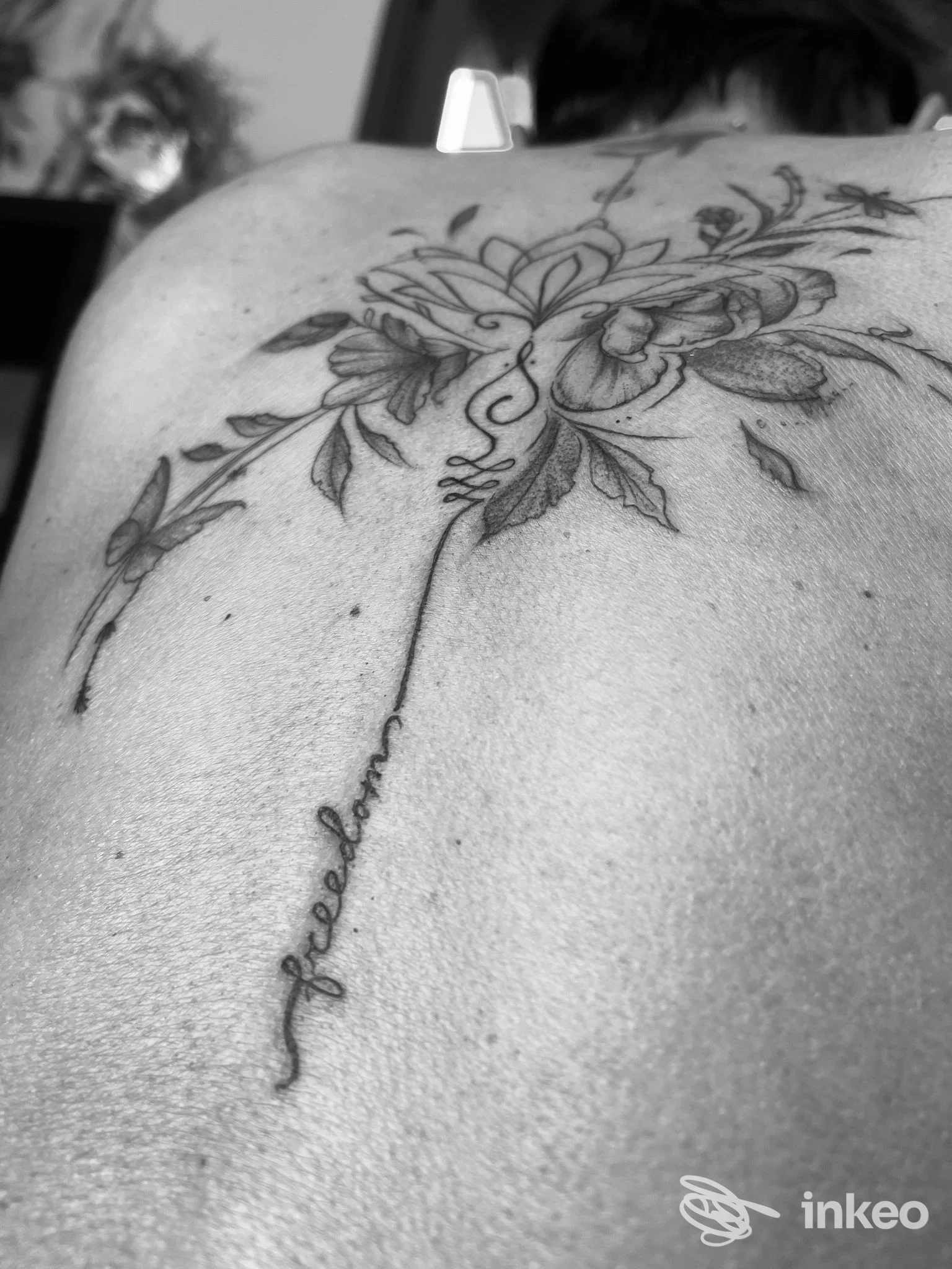 Schiena tatuata con motivo floreale e scritta corsiva, foto inviata da Claudia ink lab a Guiglia.