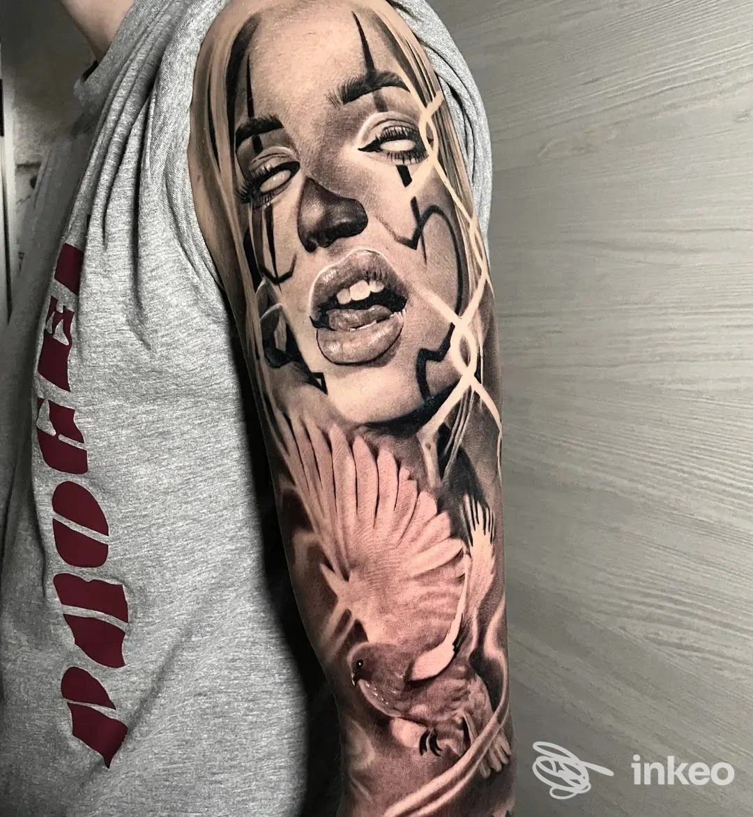 Ampio tatuaggio realistico in bianco e nero su braccio con volto femminile e uccello, foto fornita da SkinCake Tattoo & Piercing, Santarcangelo di Romagna.