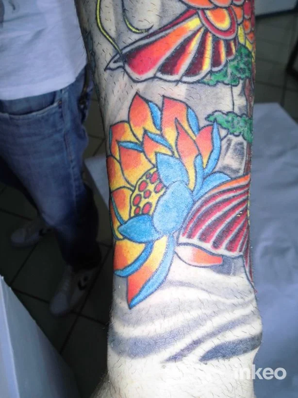 Primo piano di un tatuaggio floreale a colori sull'avambraccio, Image Studio Simone Tattoo, Fossa.