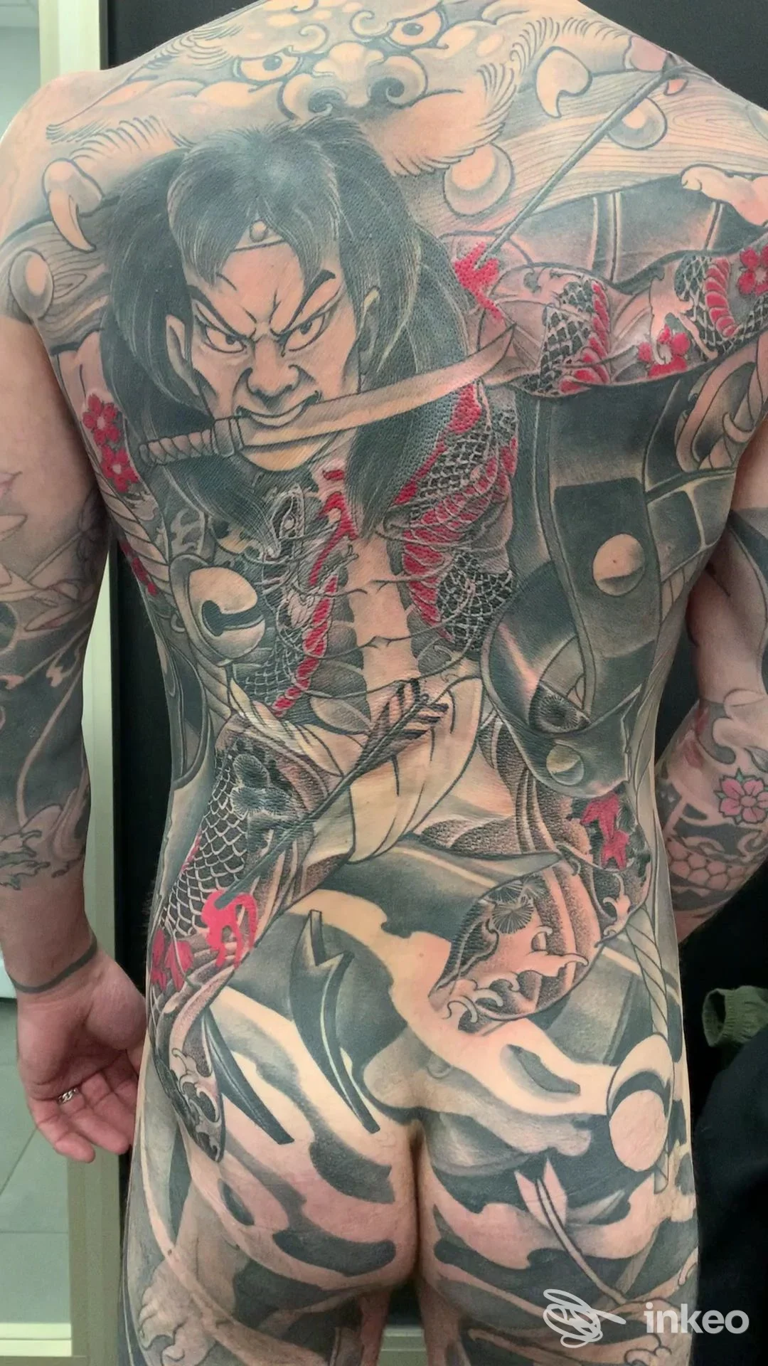 Ampio tatuaggio tradizionale sulla schiena e glutei, figura di guerriero in nero, grigio e rosso, lavoro di Holy Light Tattoo Shop a Rubiera.