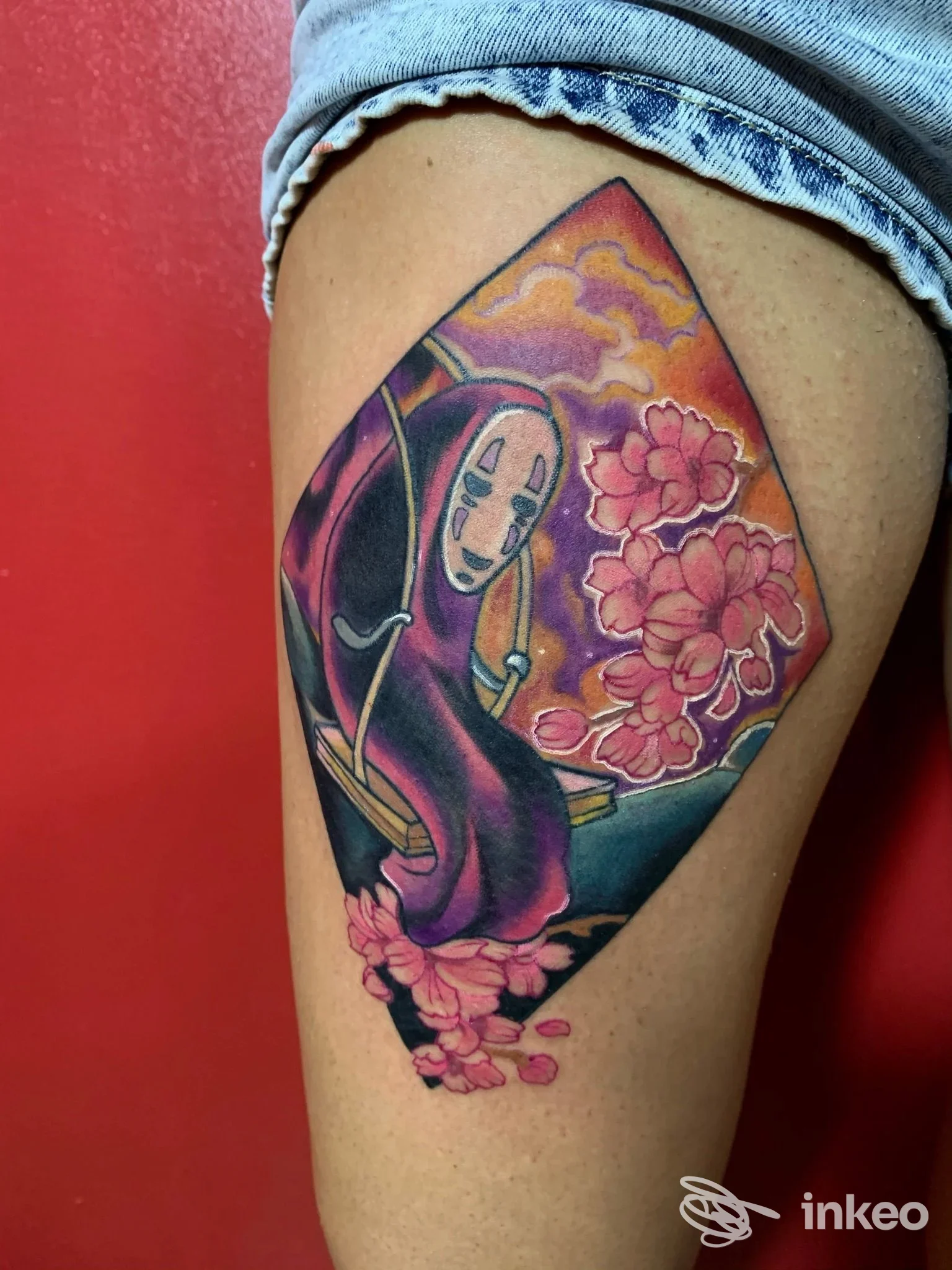 Tatuaggio colorato su coscia con figura mascherata e fiori di ciliegio, foto fornita da I Moda' Tattoo Factory, Collecchio.