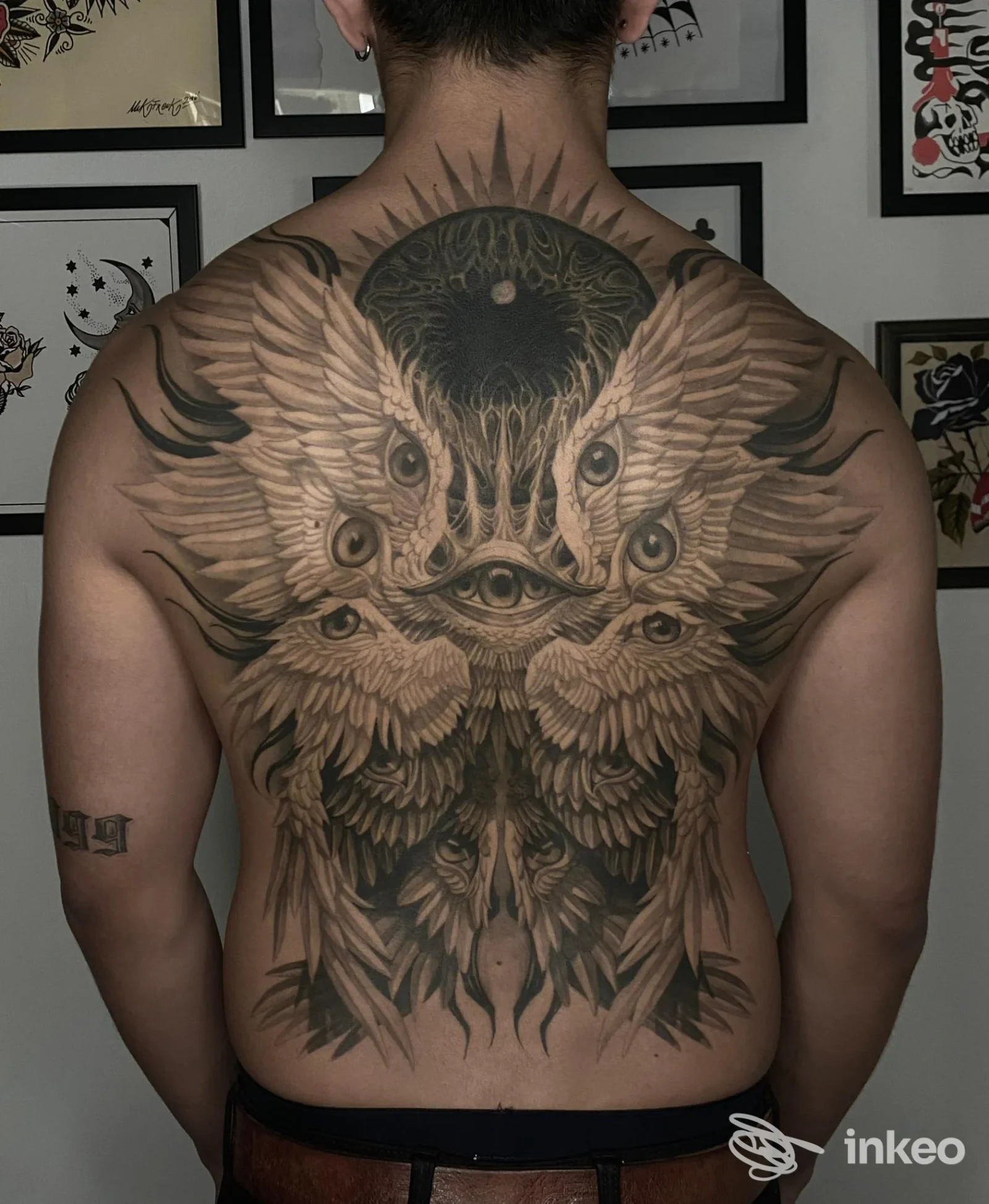 Grande tatuaggio che copre l'intera schiena con ali e occhi, realizzato da Black Swan Tattoo a Rimini.