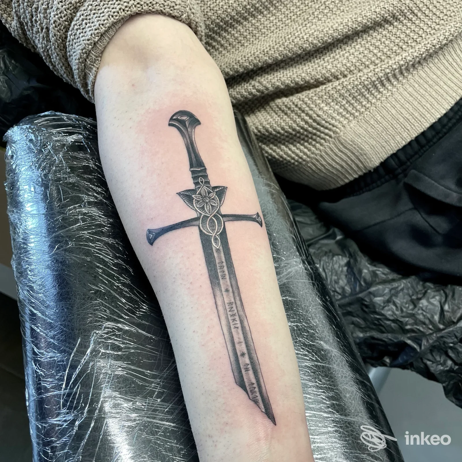 Tatuaggio in nero e grigio di una spada sull'avambraccio, Black Swan Tattoo, Rimini