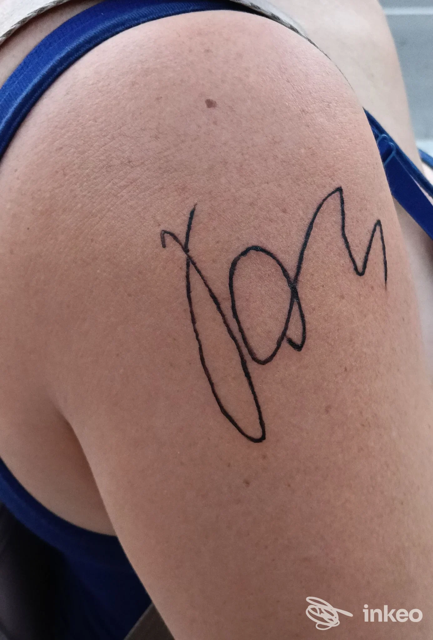 Tatuaggio a inchiostro nero a forma di firma sulla spalla, foto inviata da Chesta Creations Tattoo a Zocca.