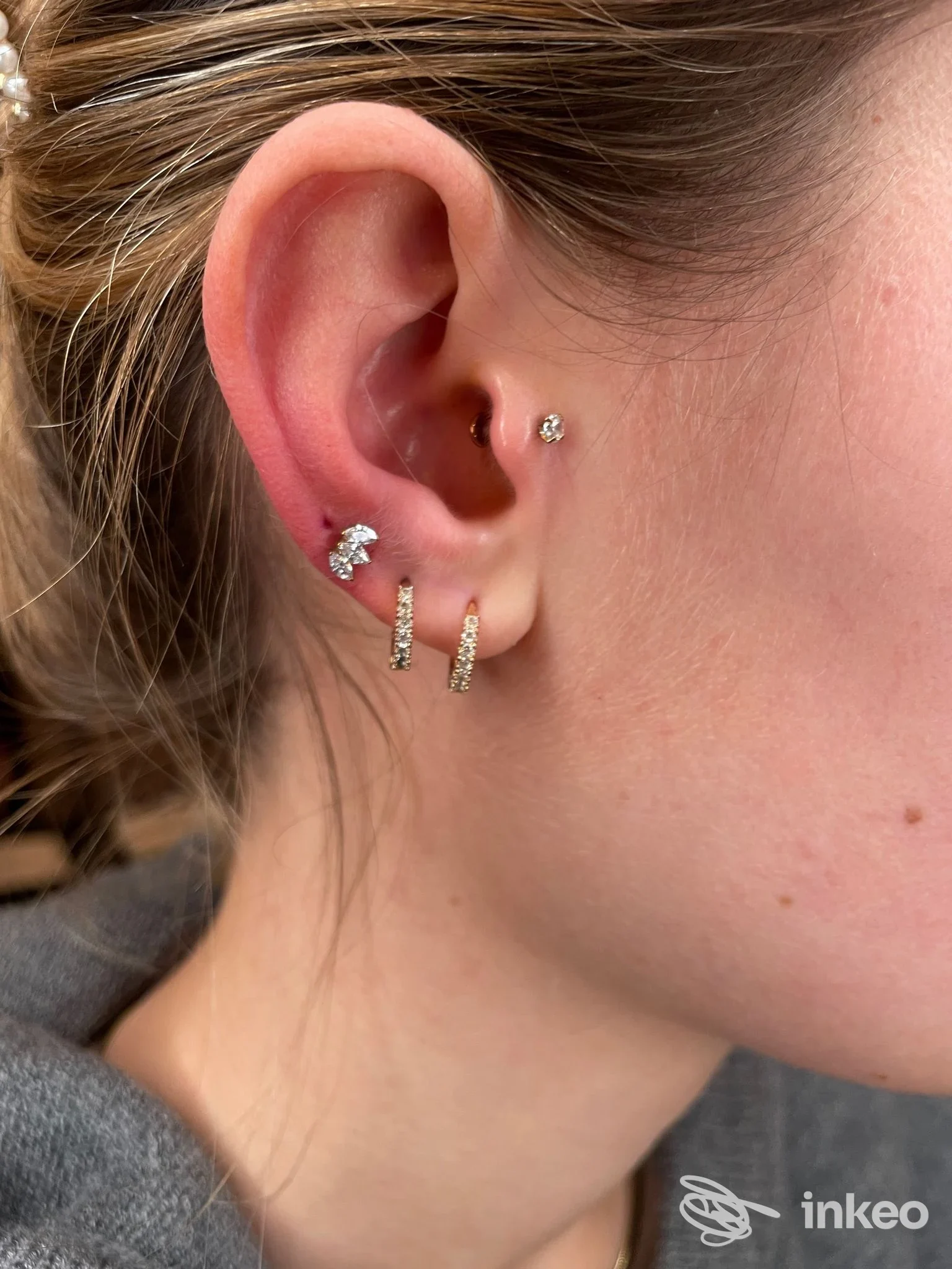 Dettaglio di orecchio con più piercing realizzati presso AdamantioTattoo&Piercing, Piacenza: lobo con anellini e piccolo brillante sulla cartilagine.