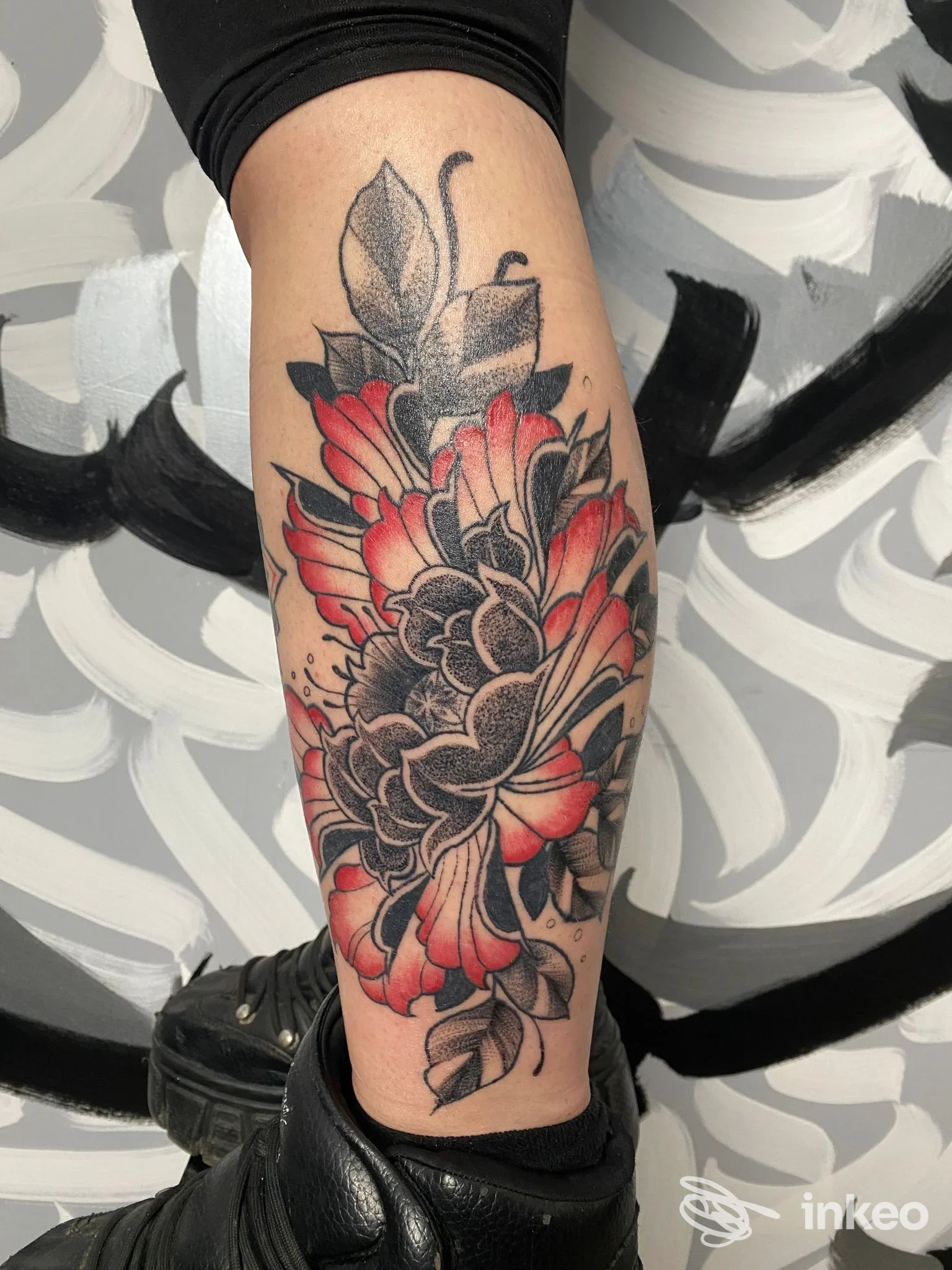 Tatuaggio floreale rosso e nero sul polpaccio, realizzato da Spleen Tattoo Studio a San Polo di Torrile.